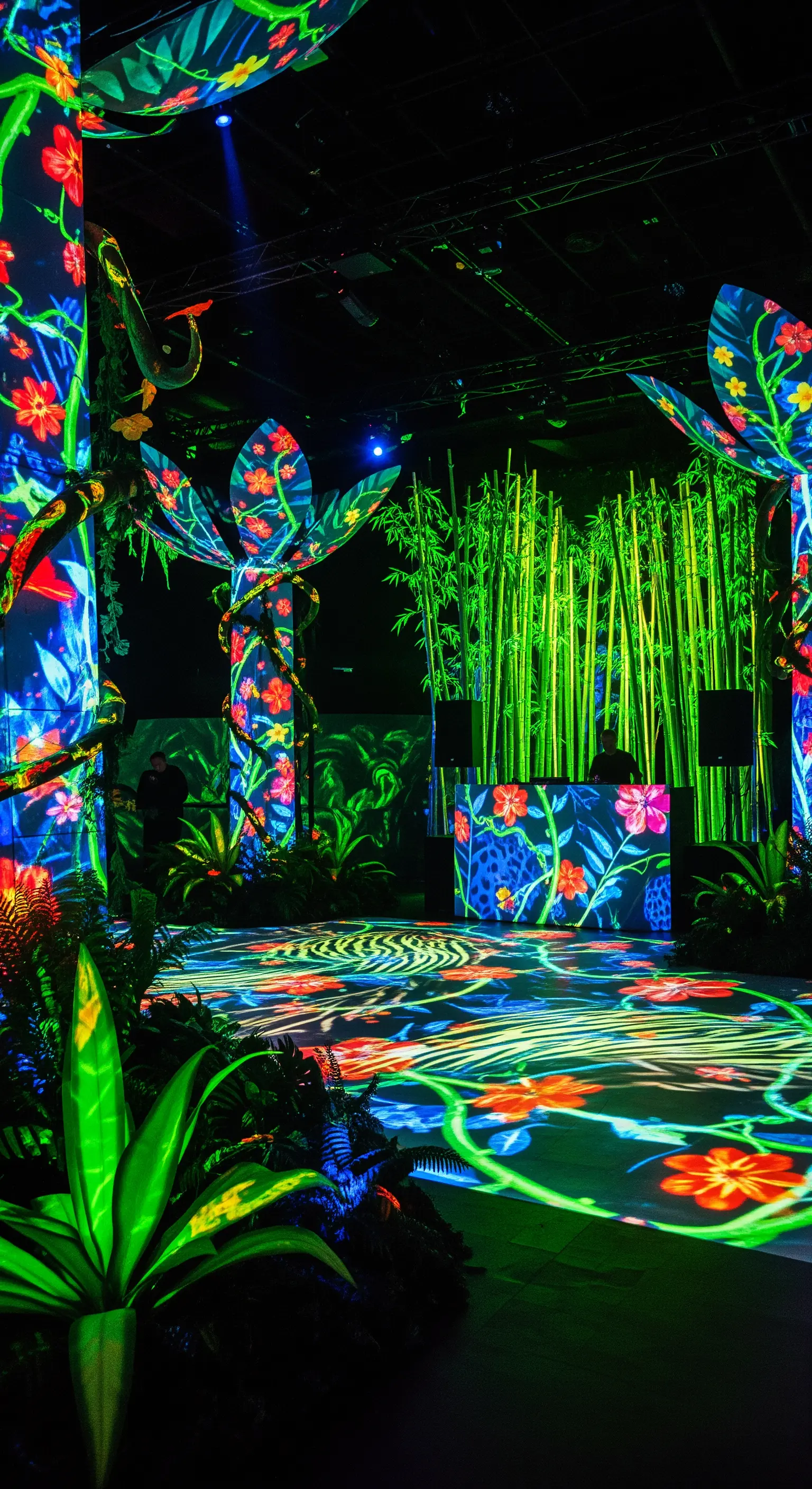Pista da ballo in una giungla con proiezioni di fiori fluorescenti su piante e colonne.