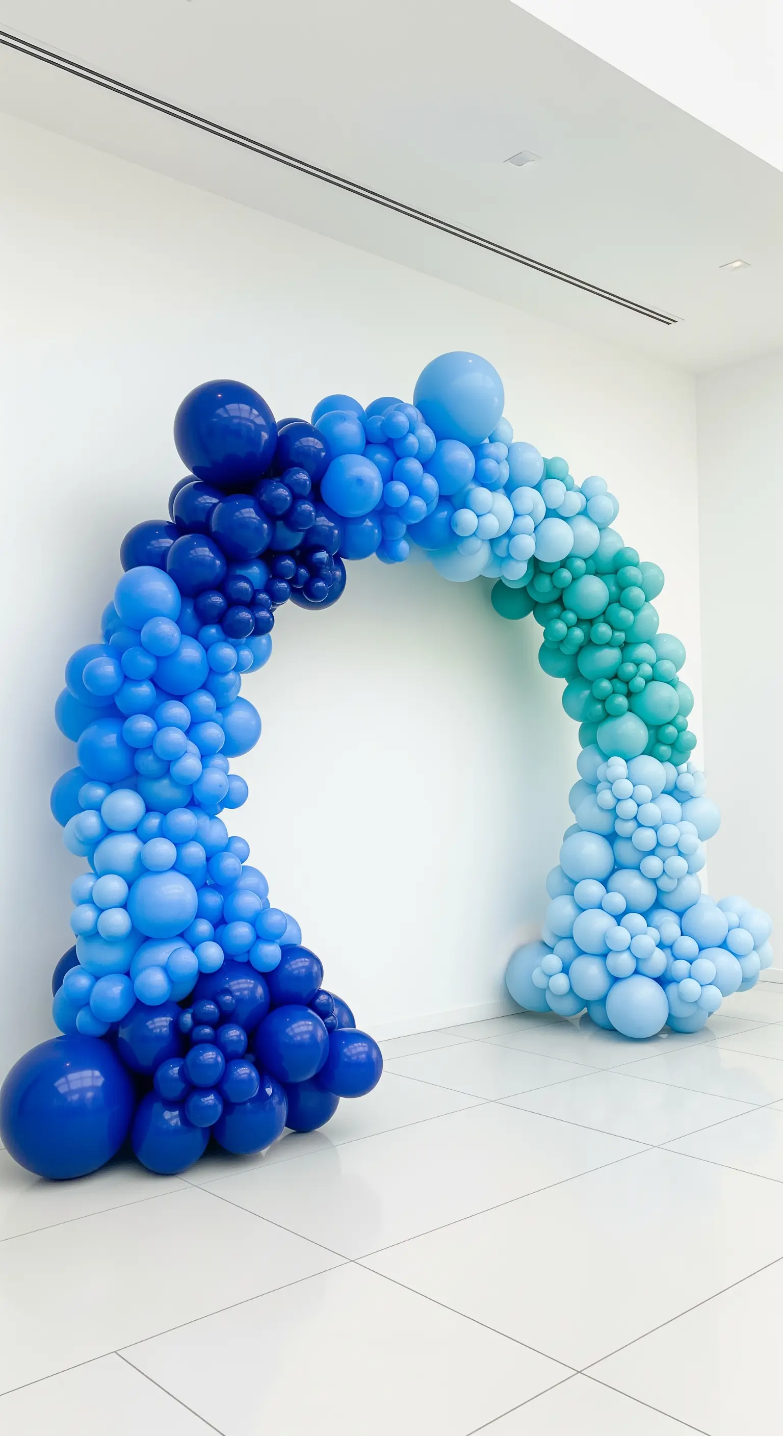 Arco di palloncini con effetto ombré che sfuma dal blu scuro al turchese chiaro.