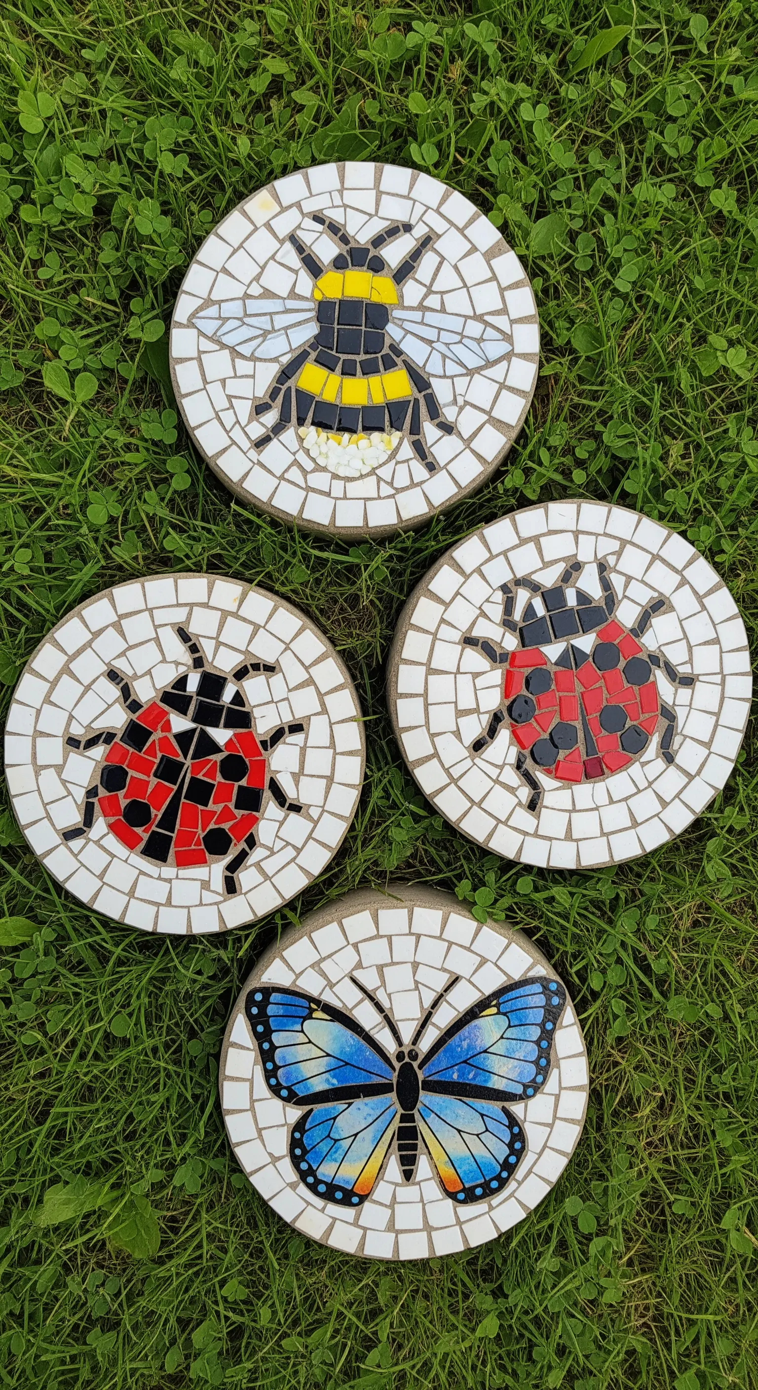 Pietre da giardino rotonde con mosaici che raffigururano una coccinella, un'ape e una farfalla.