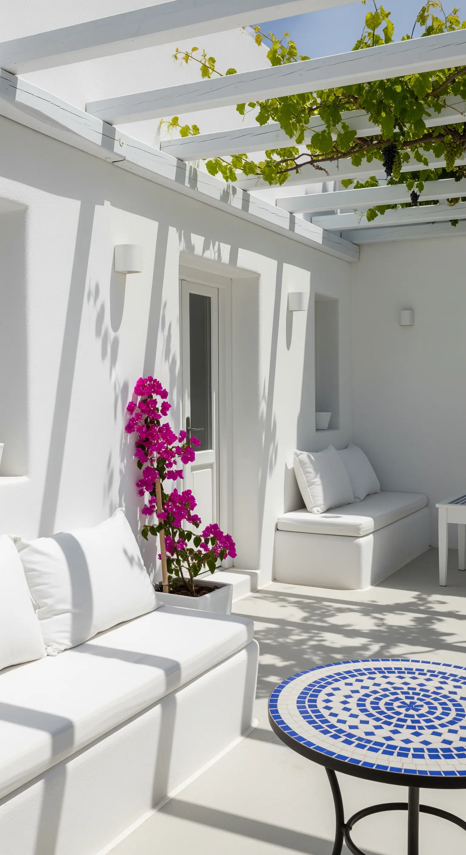 Terrazza minimalista total white con divani in muratura e un tavolo in mosaico blu.