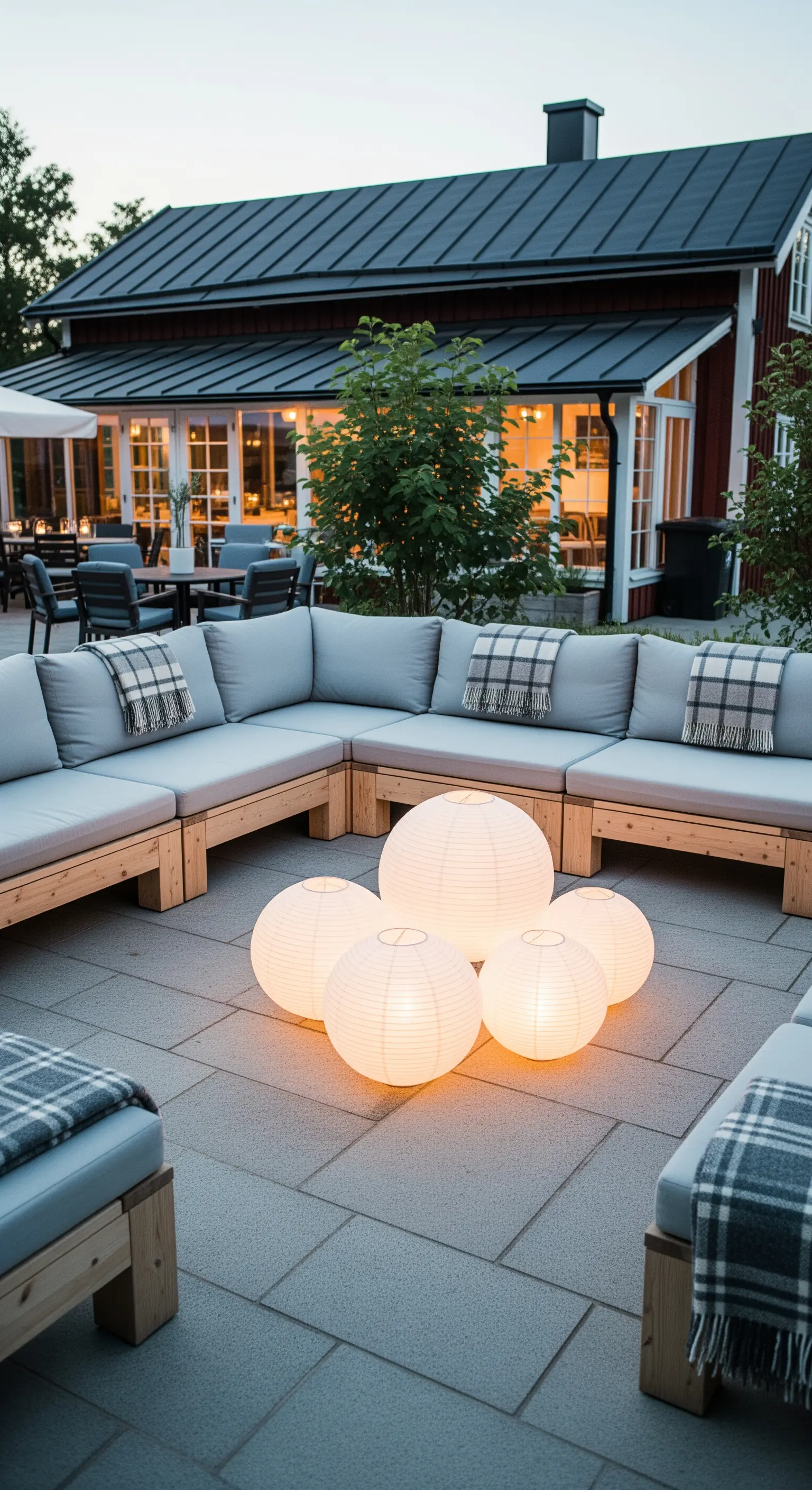 Grande divano angolare grigio con al centro un gruppo di lanterne sferiche di carta illuminate.