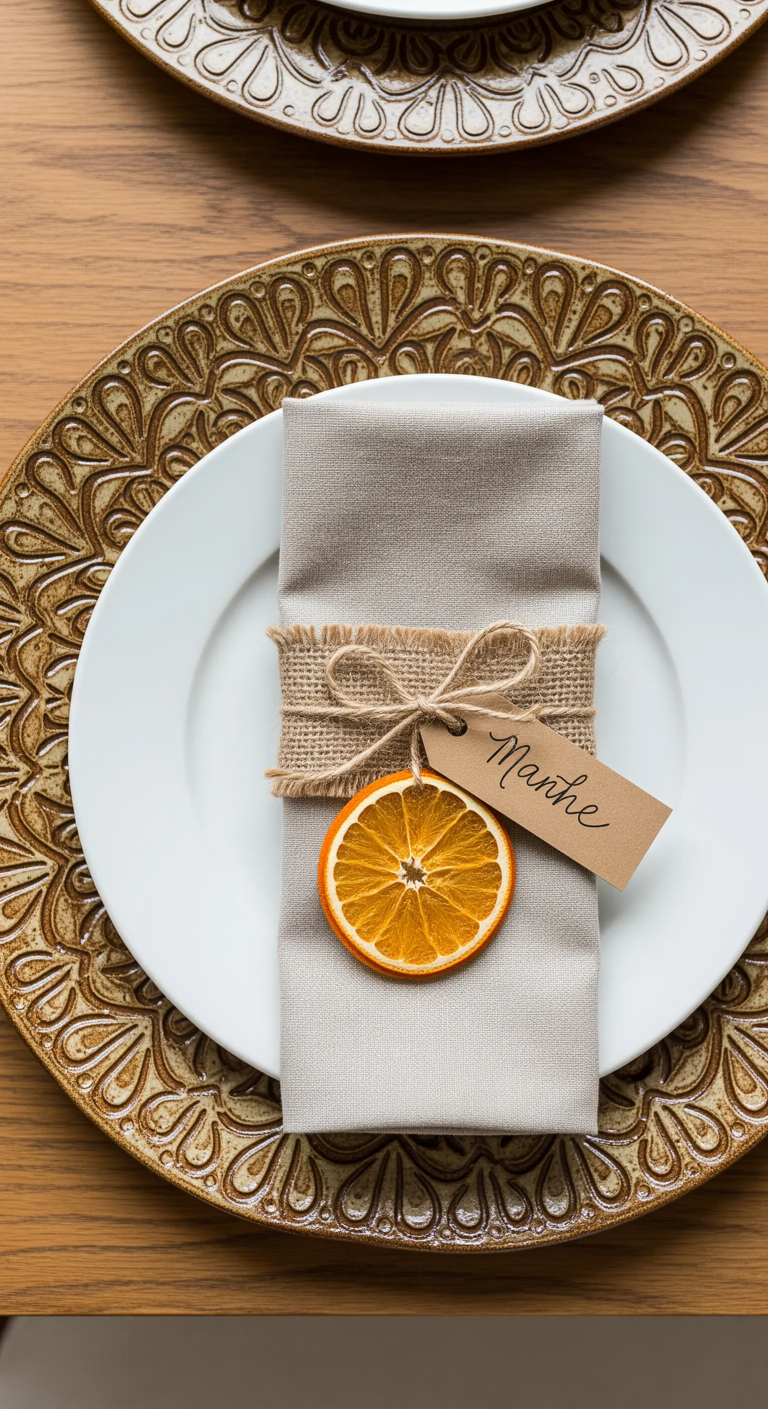 Close-up di un segnaposto con tovagliolo in lino, etichetta scritta a mano e arancia essiccata
