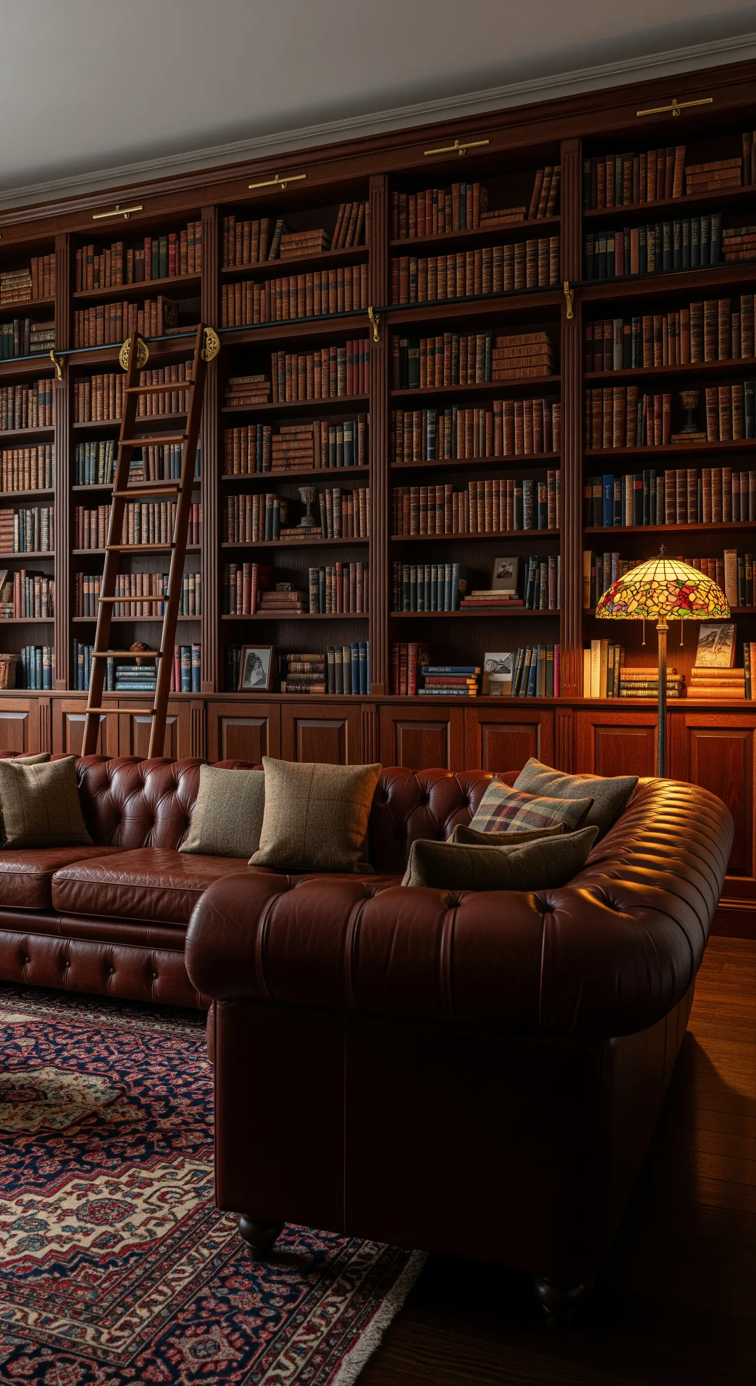 Salotto classico con libreria in legno scuro, divano Chesterfield e scala a pioli.
