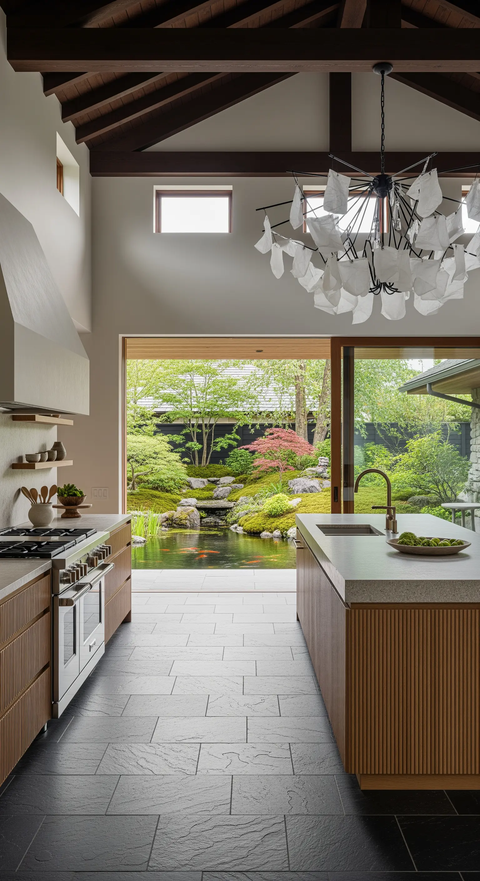 Cucina con isola in legno cannettato e lampadario scultoreo con elementi bianchi