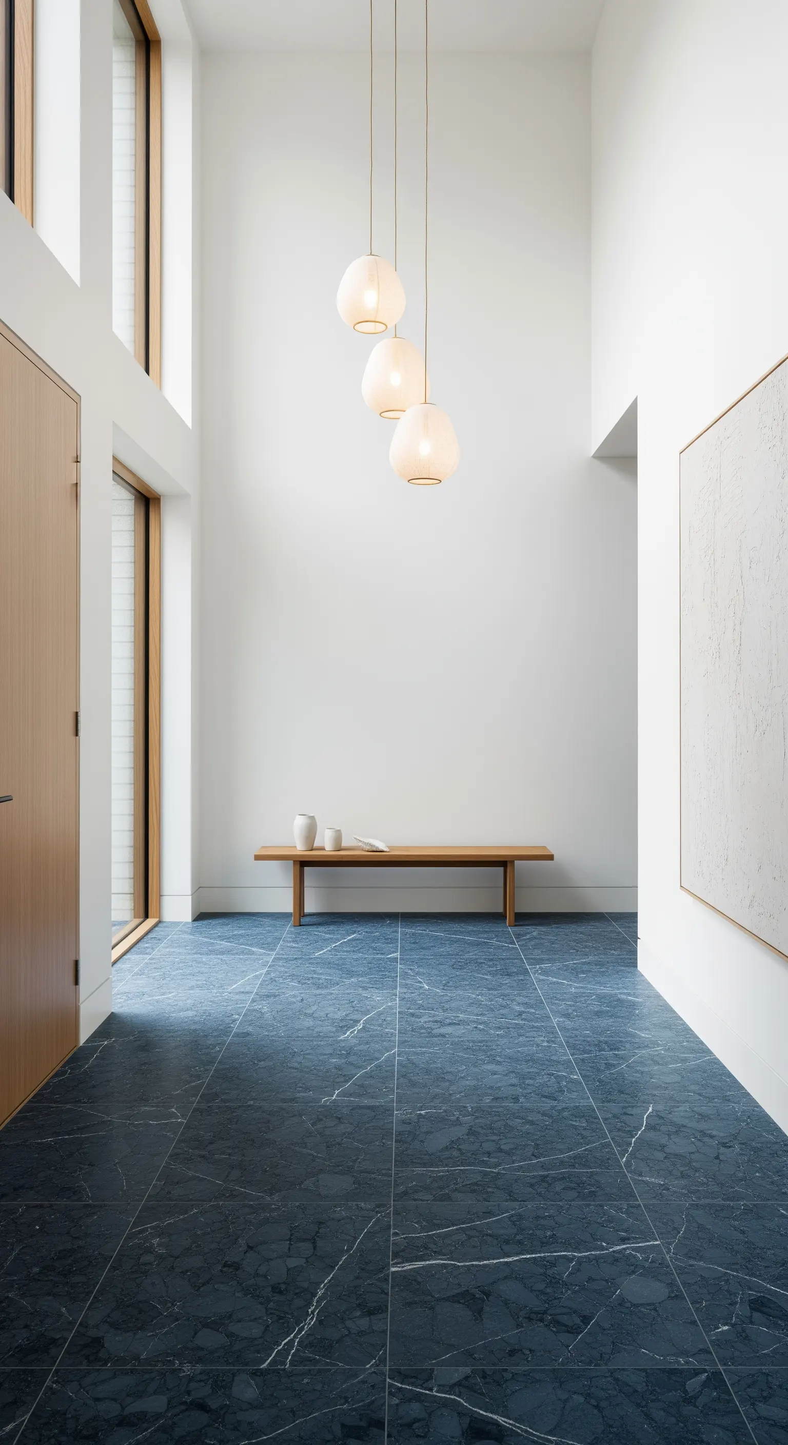 Ingresso minimalista con pavimento in marmo blu, pareti bianche e una panca in legno.