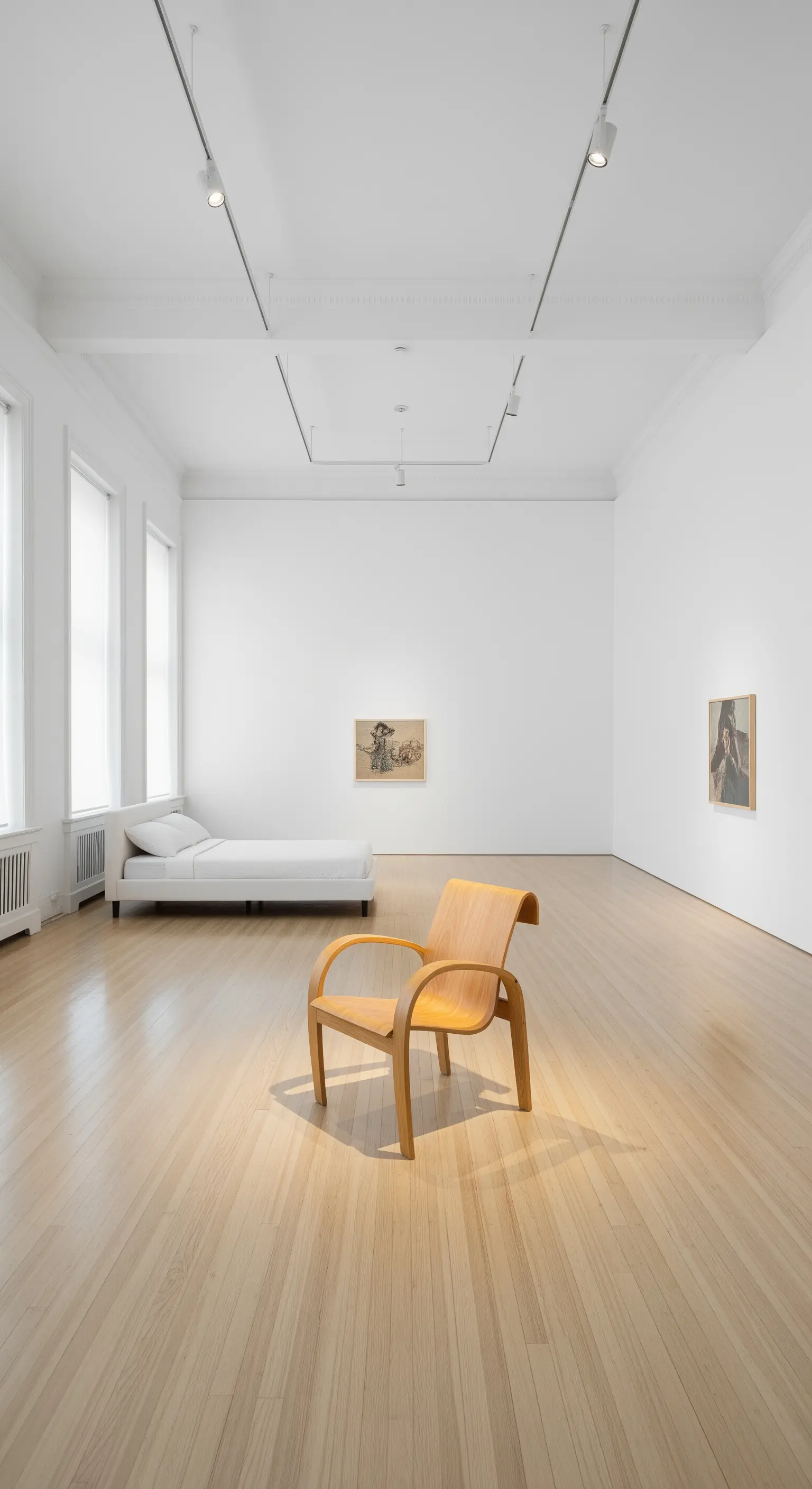 Ampia stanza bianca con letto singolo e una sedia di design in legno curvato.