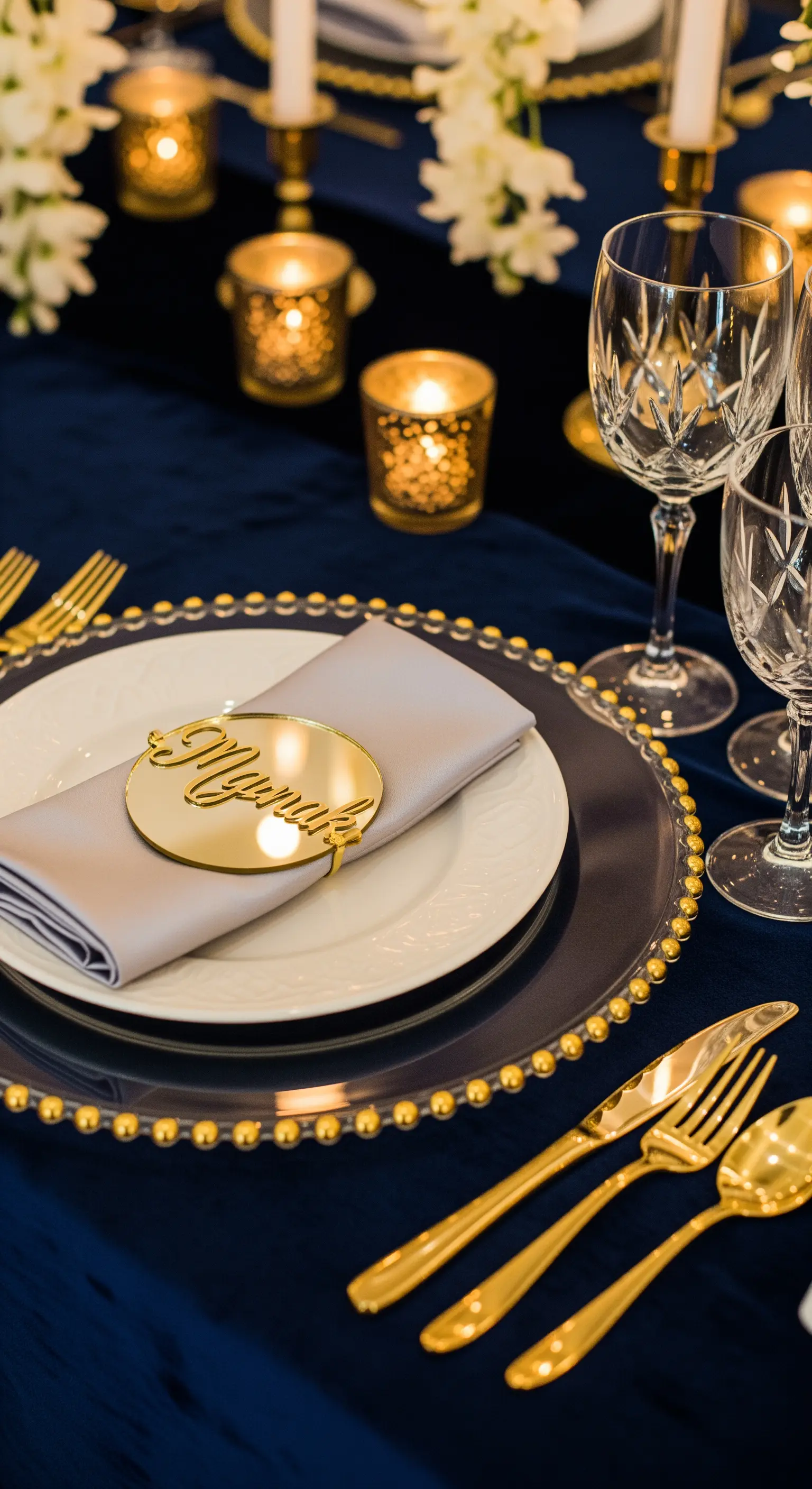 Dettaglio di un segnaposto dorato a specchio su un piatto con bordo di perline dorate.