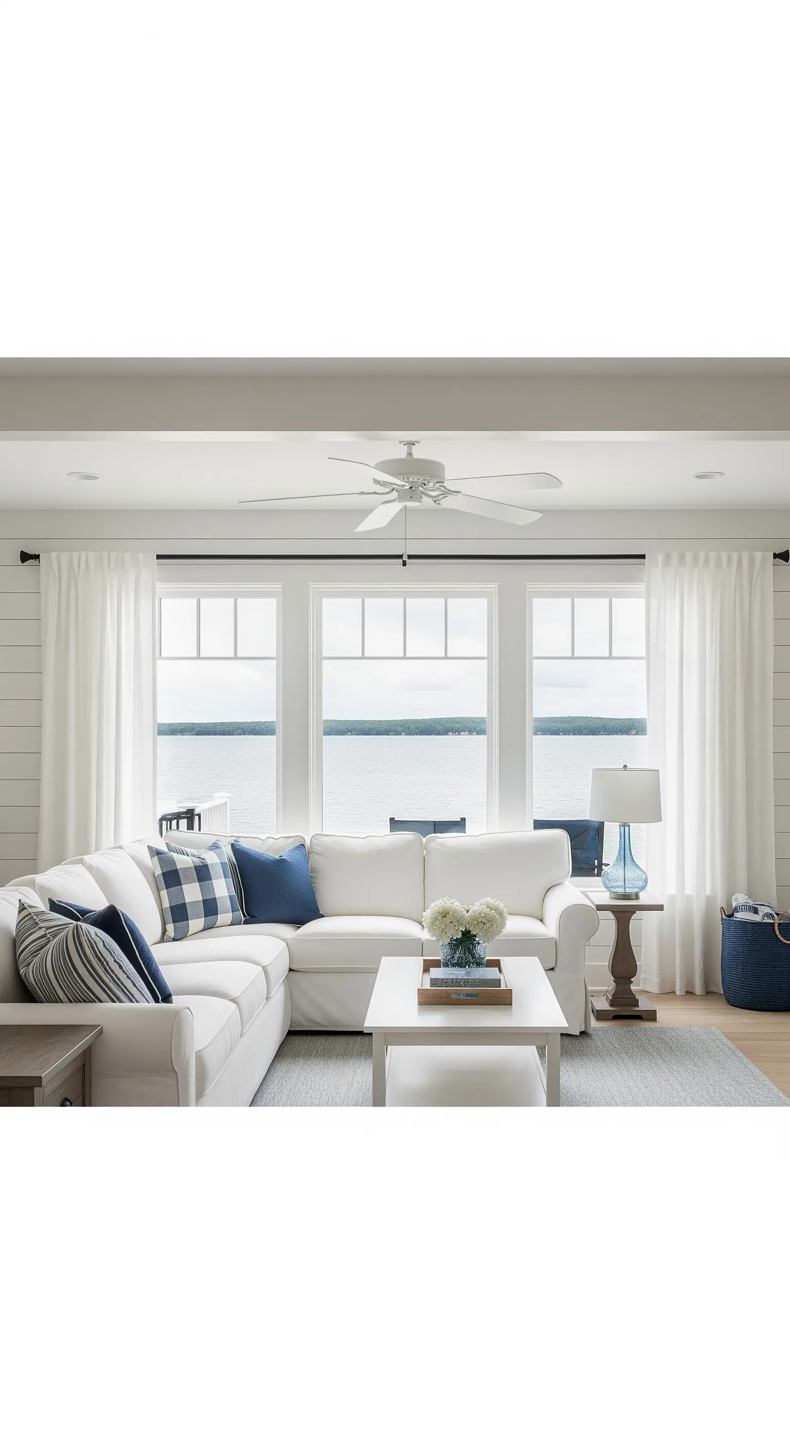 Divano componibile bianco con cuscini a quadri blu e bianchi di fronte a una finestra sul mare.