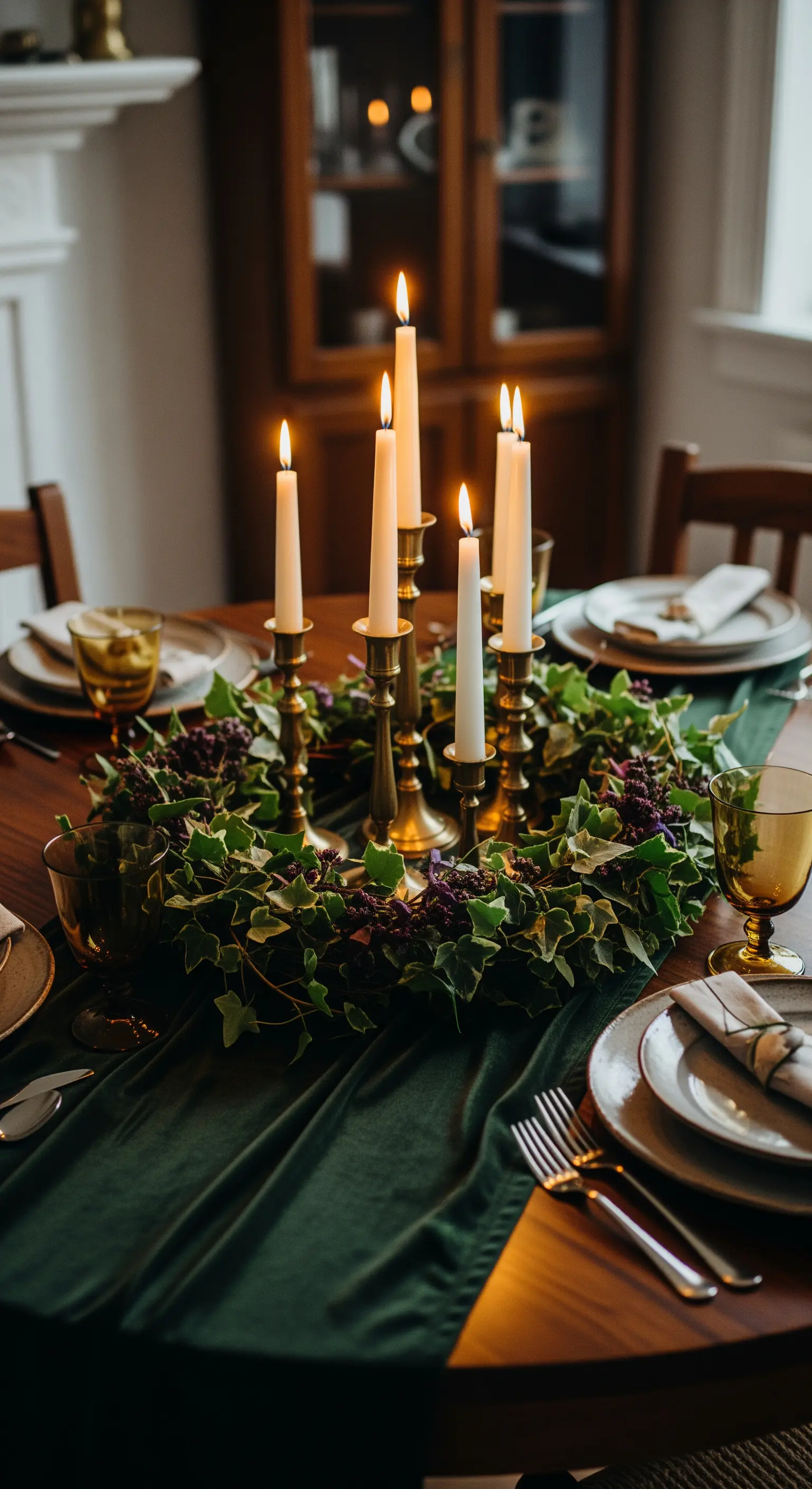 Tavola elegante con runner in velluto verde, candelabri in ottone e ghirlanda di edera