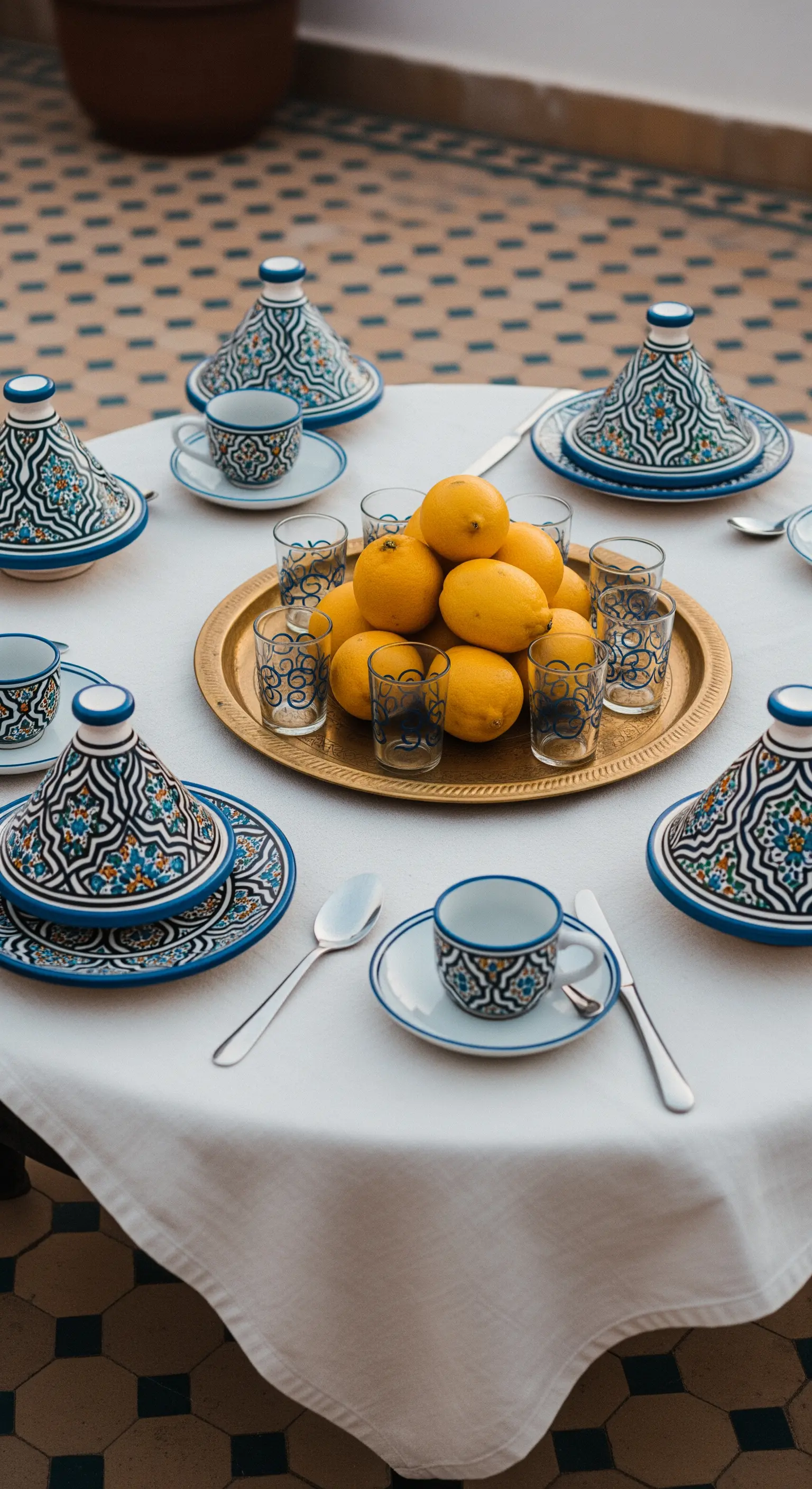 Tavola in stile marocchino con piatti decorati, tajine e un vassoio d'ottone con limoni.