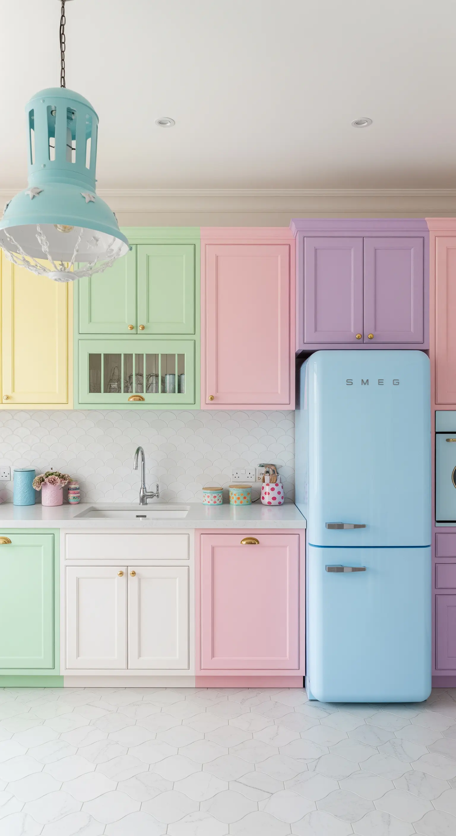 Cucina con mobili di diversi colori pastello e frigorifero azzurro Smeg.