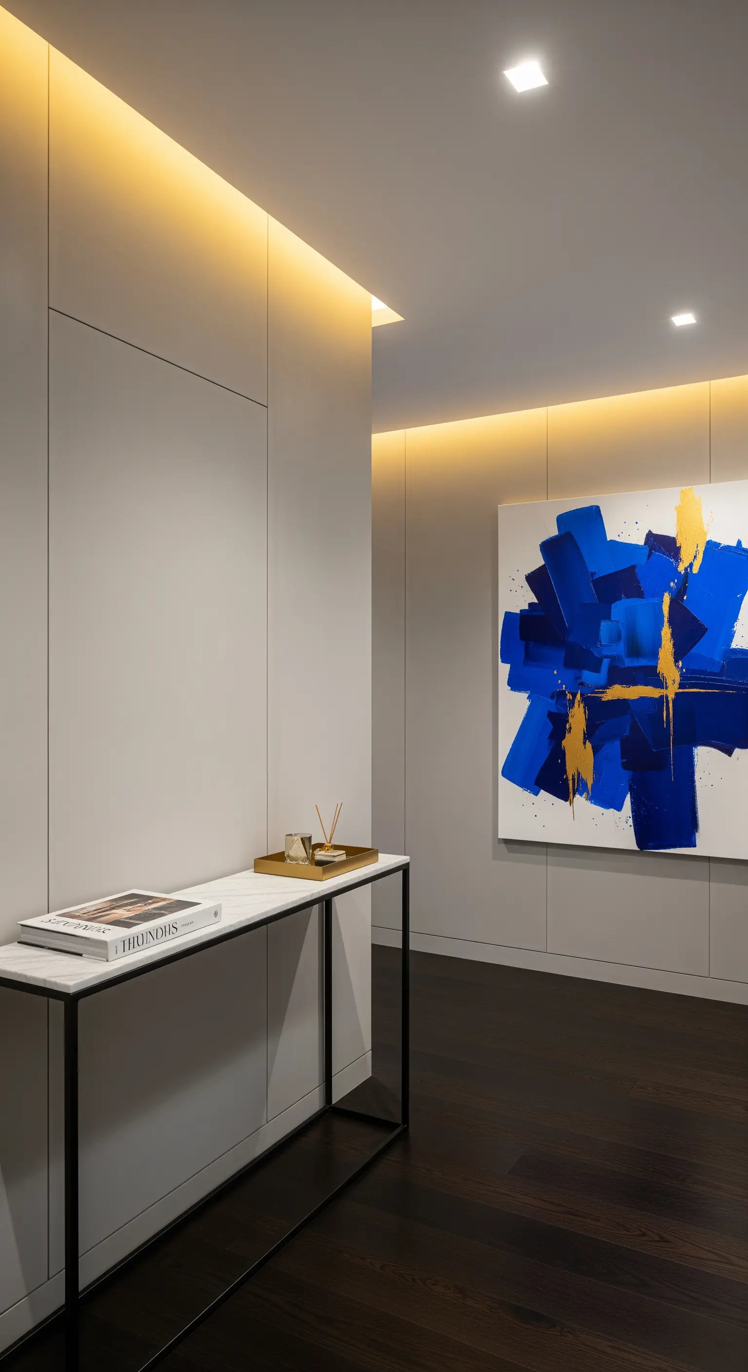 Corridoio minimalista con illuminazione a LED integrata e un grande quadro astratto blu e oro.
