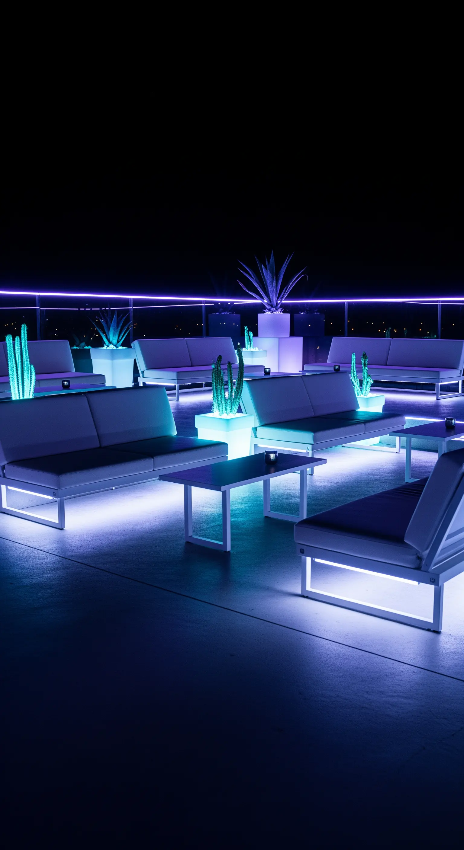 Terrazza di notte con divani e tavoli bianchi illuminati da luci a LED viola.