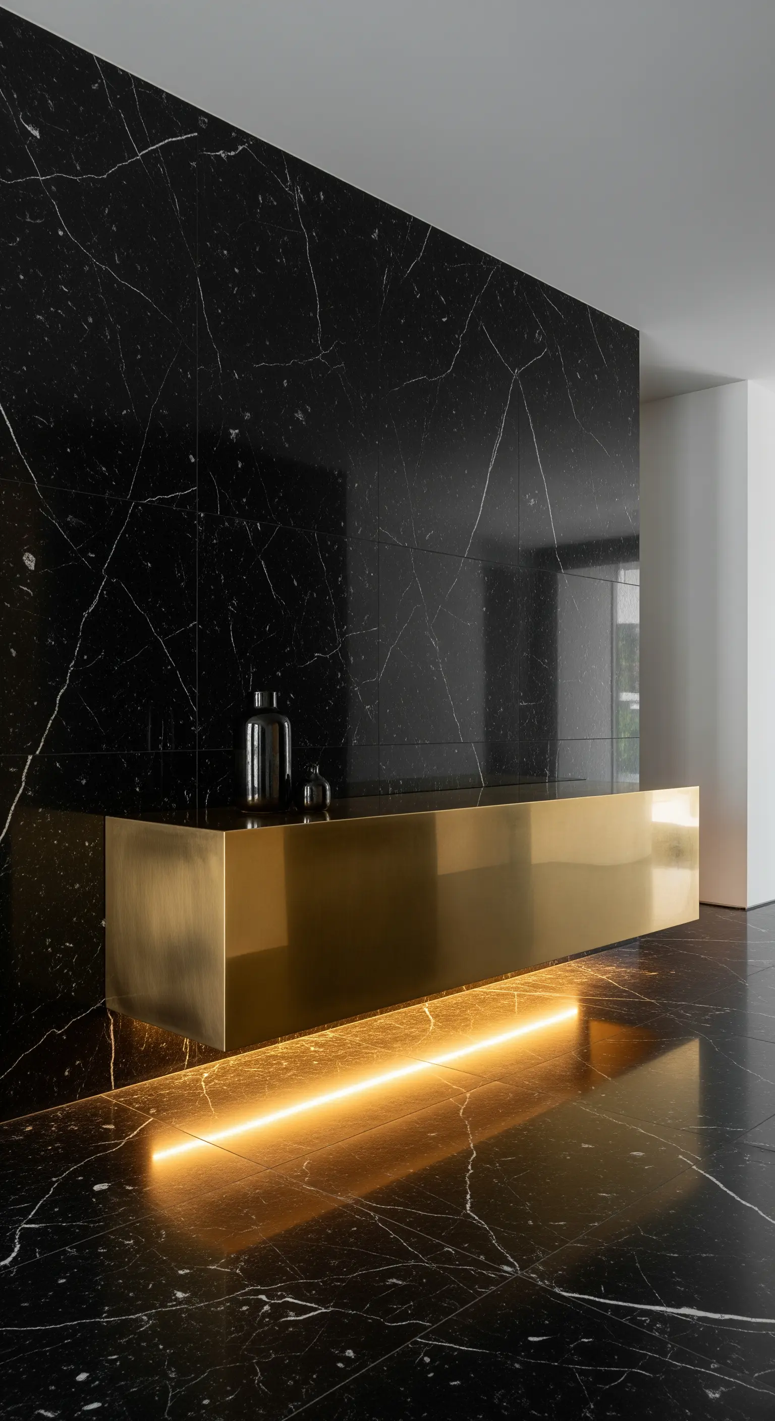 Consolle sospesa in ottone spazzolato contro una parete di marmo nero con venature bianche.