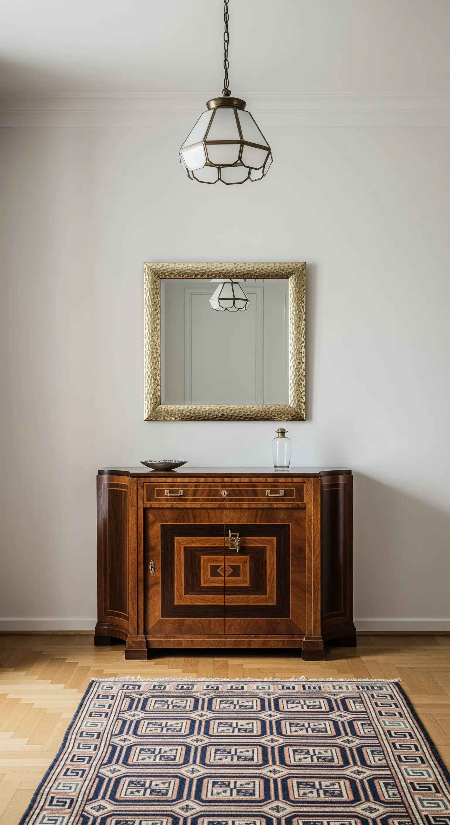 Ingresso Mid-Century con credenza intarsiata, specchio in ottone e tappeto geometrico.