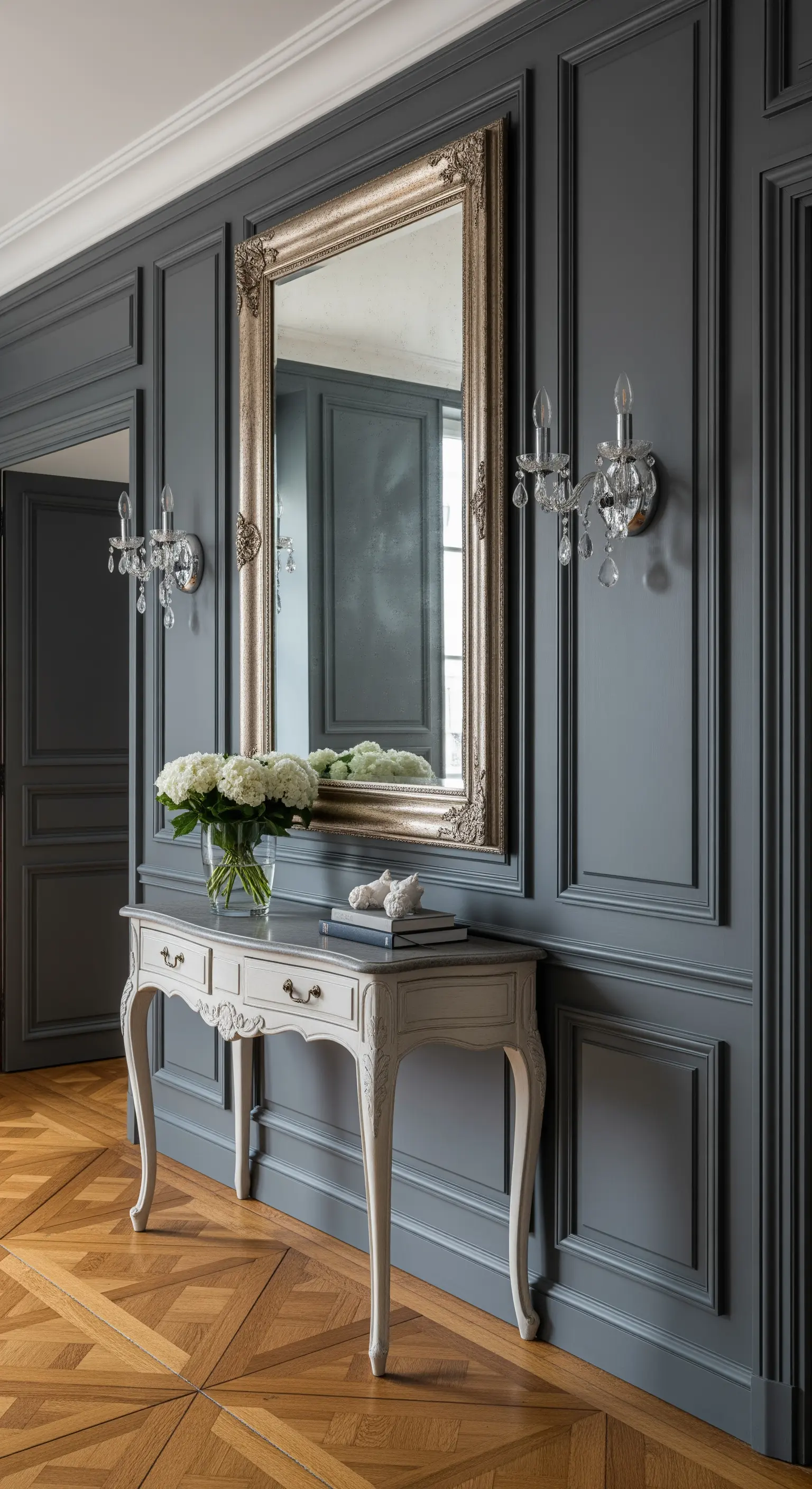 Ingresso con boiserie grigia, consolle bianca e grande specchio con cornice argentata.