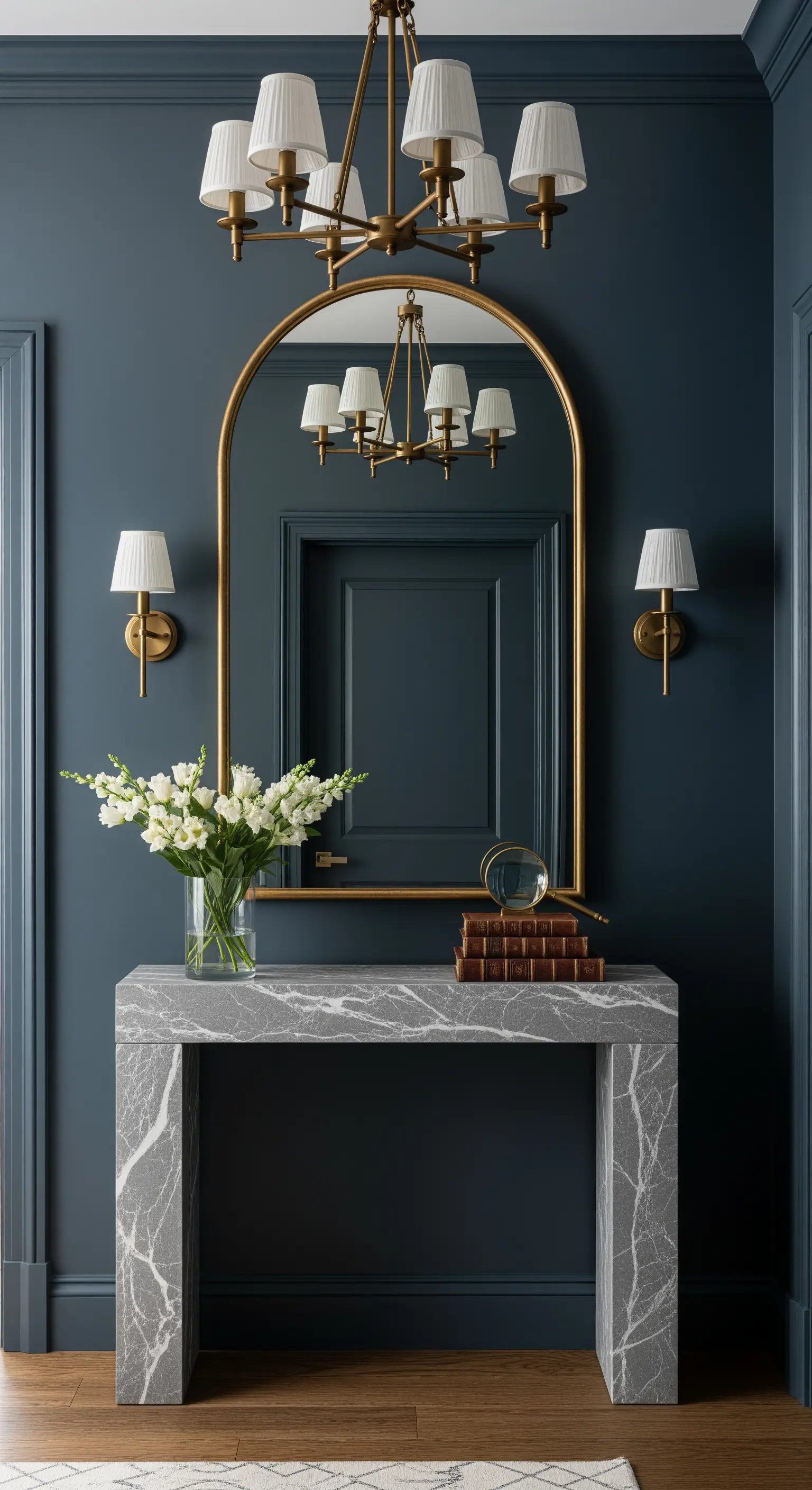 Ingresso con pareti blu-grigio, specchio ad arco dorato e consolle in marmo grigio.