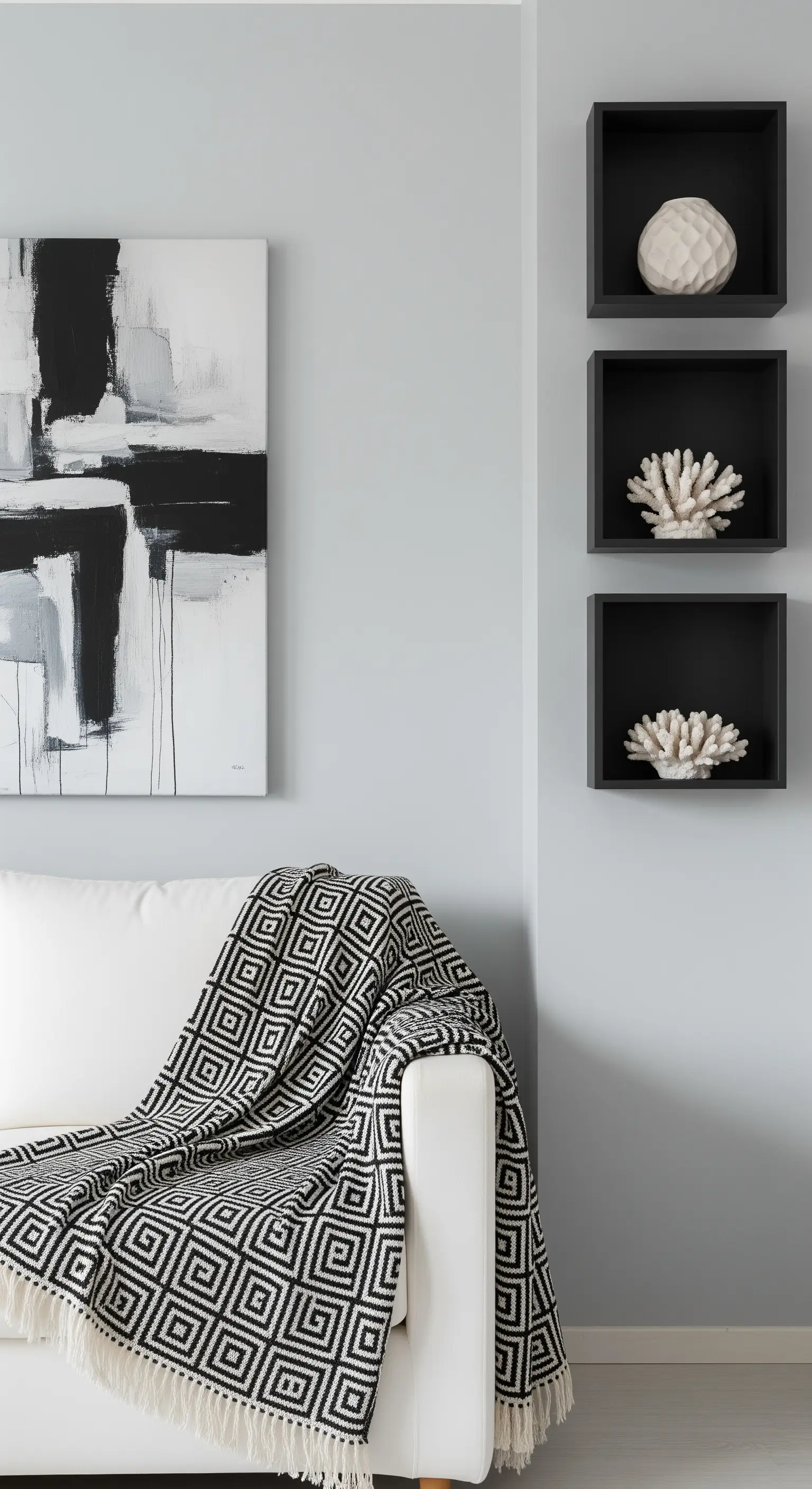 Divano bianco con coperta geometrica, quadro astratto e mensole a cubo nere.
