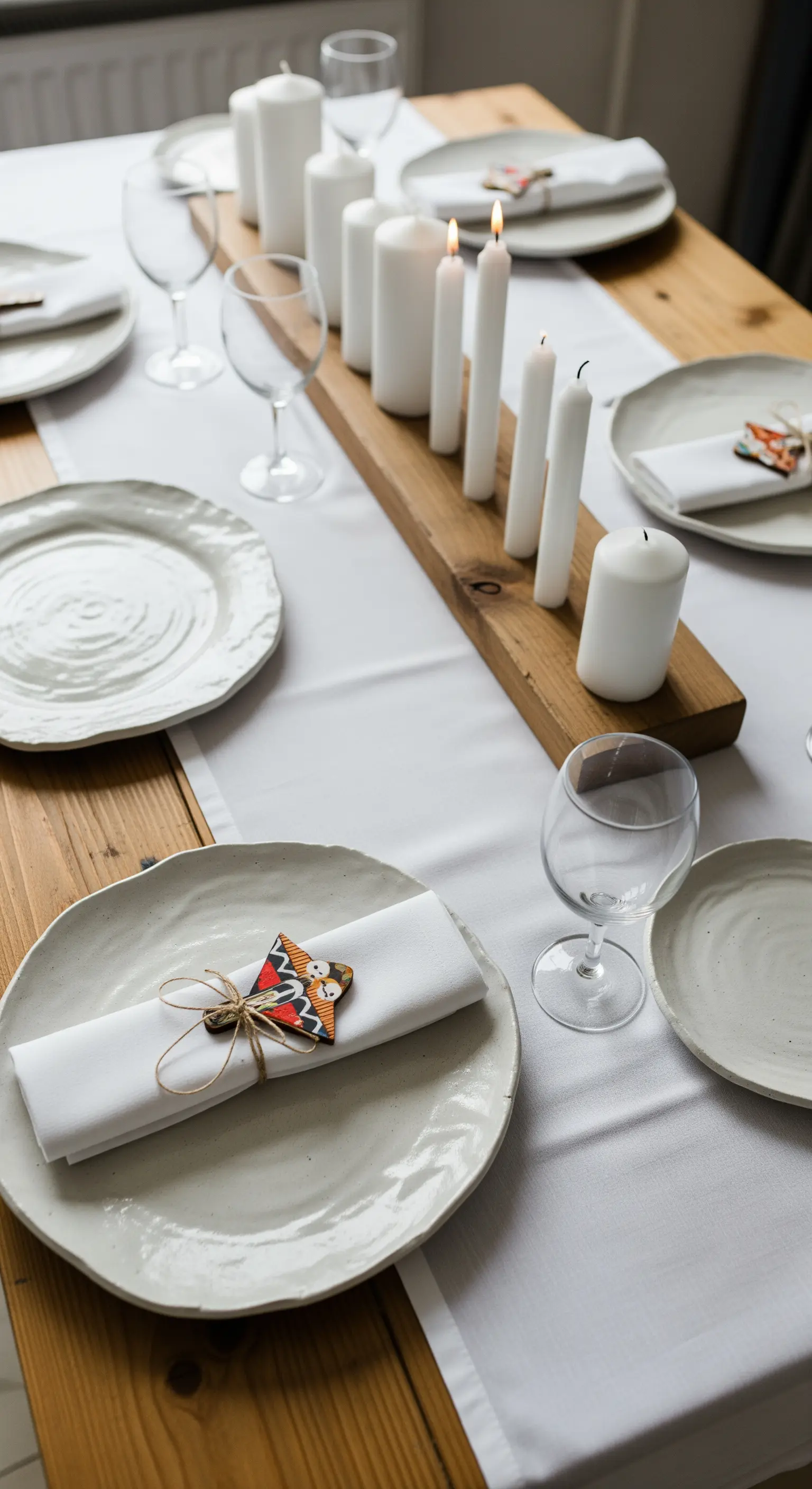 Tavola rustica con piatti in ceramica artigianale e candele su un'asse di legno.