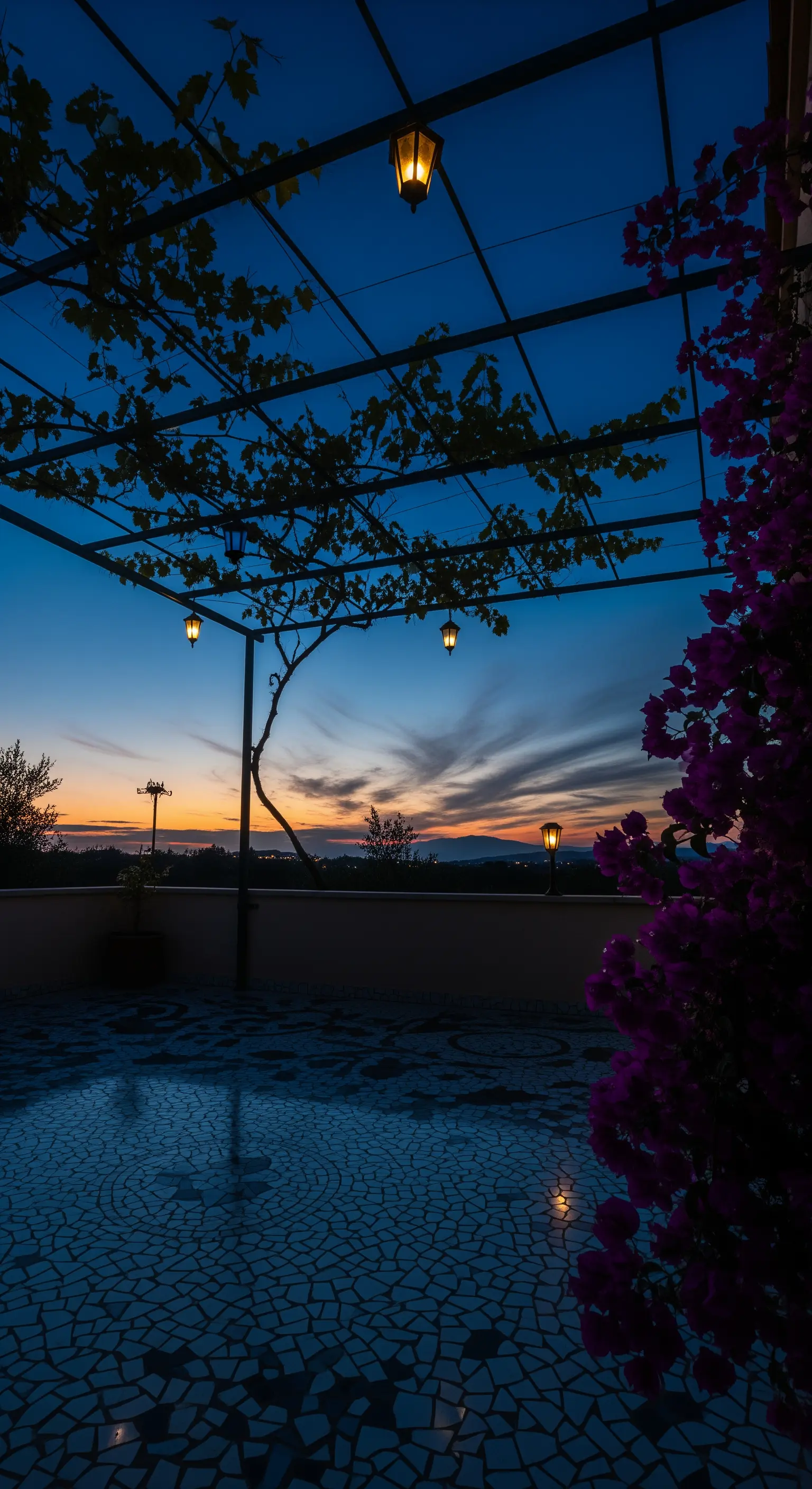Terrazza al tramonto con pavimento a mosaico e silhouette di una pergola e bouganville.