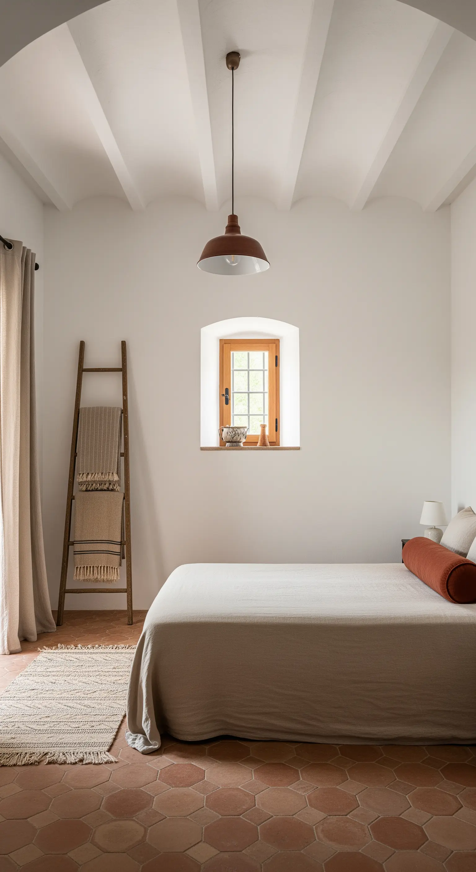 Camera da letto minimalista con pavimento in cotto esagonale e una scala in legno come appendiabiti.