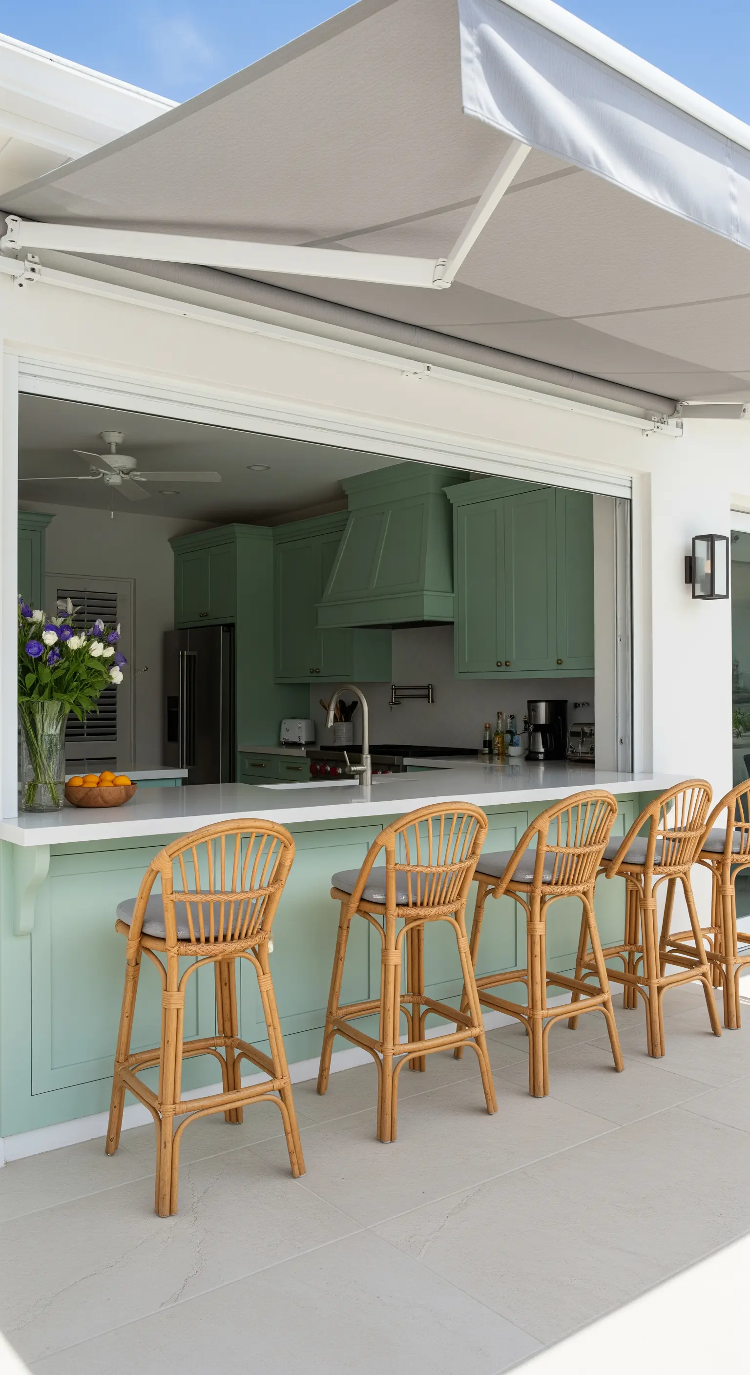 Cucina verde con grande finestra passavivande che si apre su un bancone bar esterno.