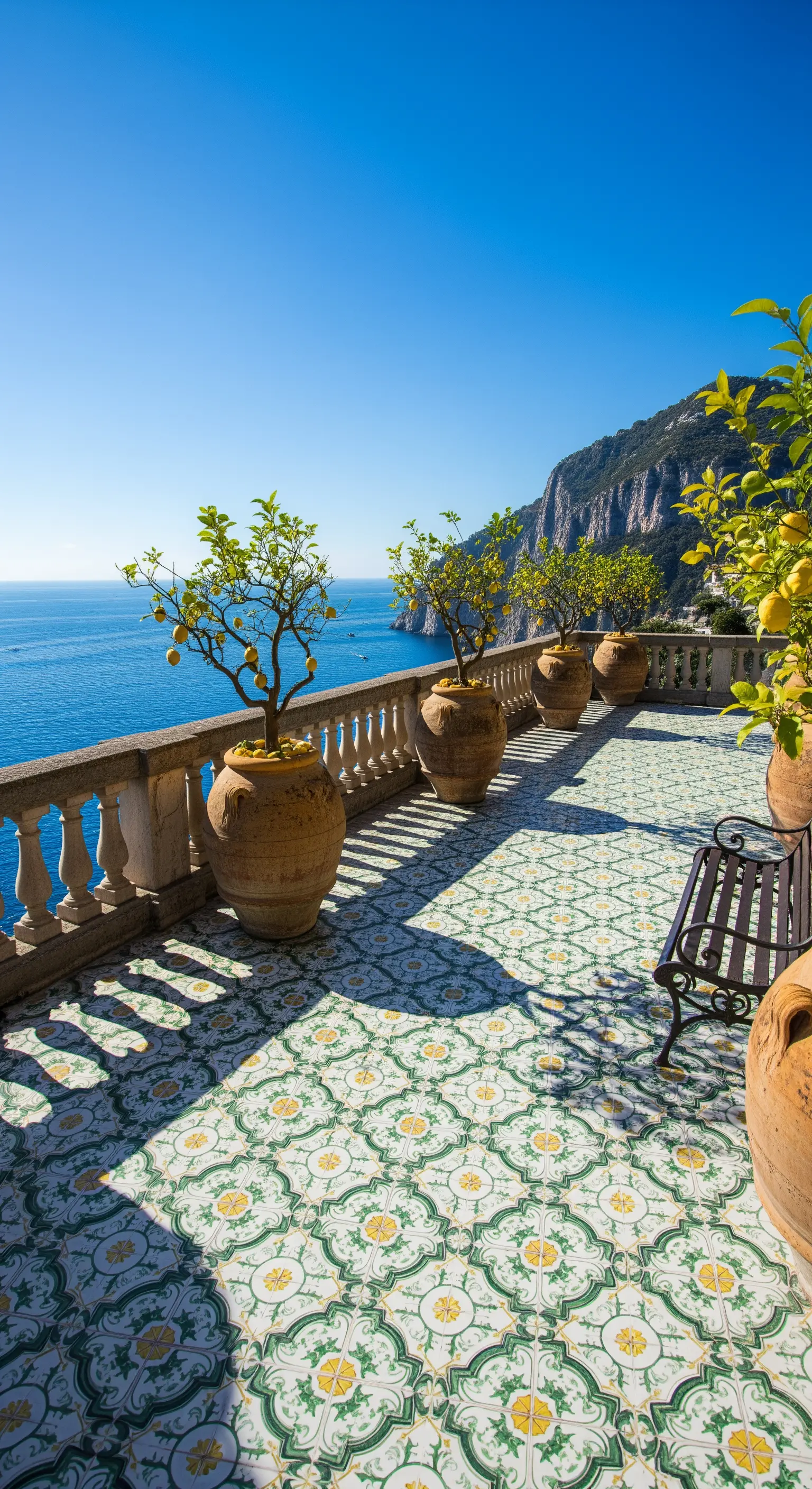 Terrazza affacciata sulla scogliera con pavimento a maioliche verdi e grandi anfore in terracotta.