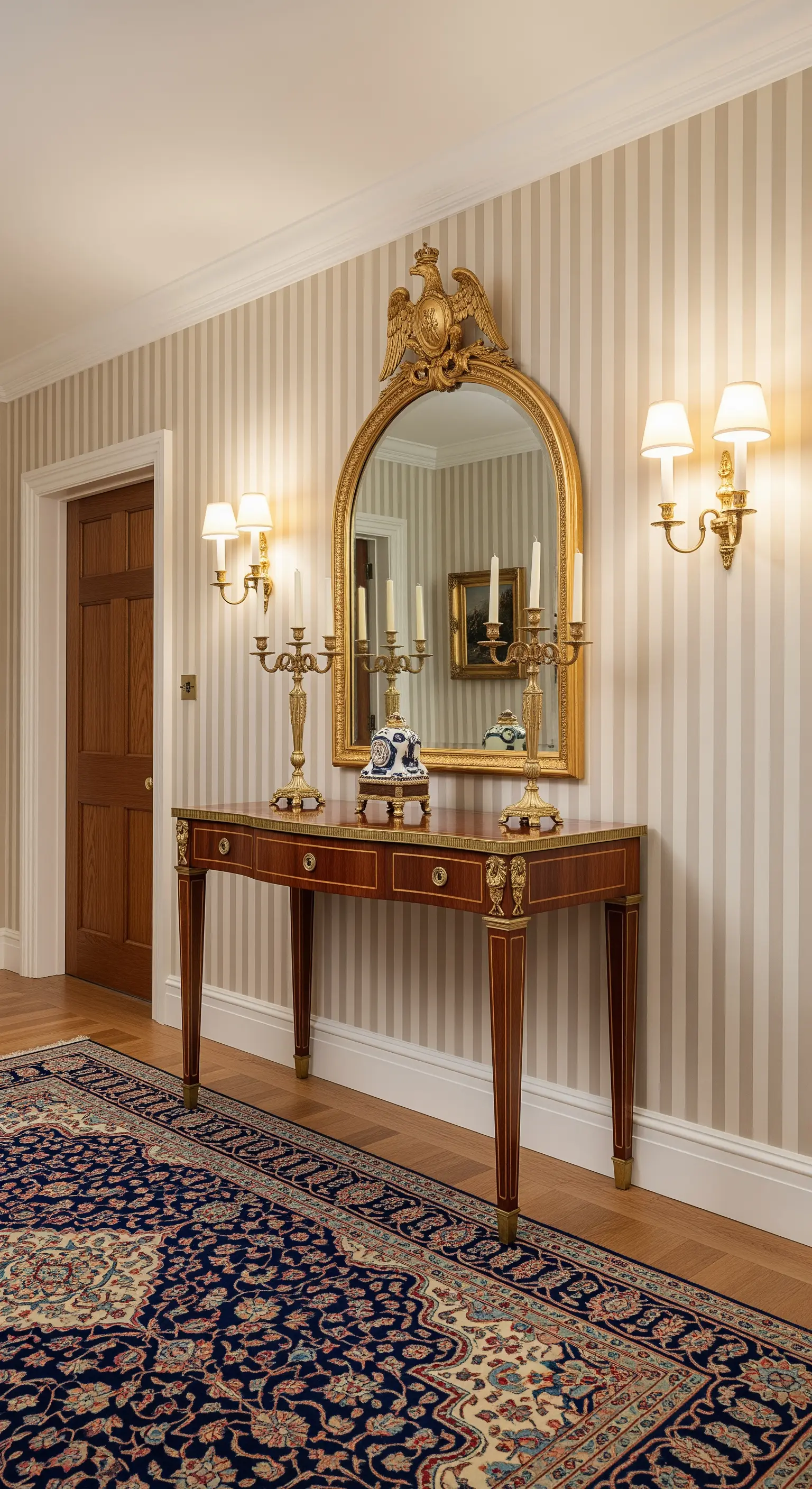 Ingresso in stile Impero con carta da parati a righe e specchio con aquila dorata.