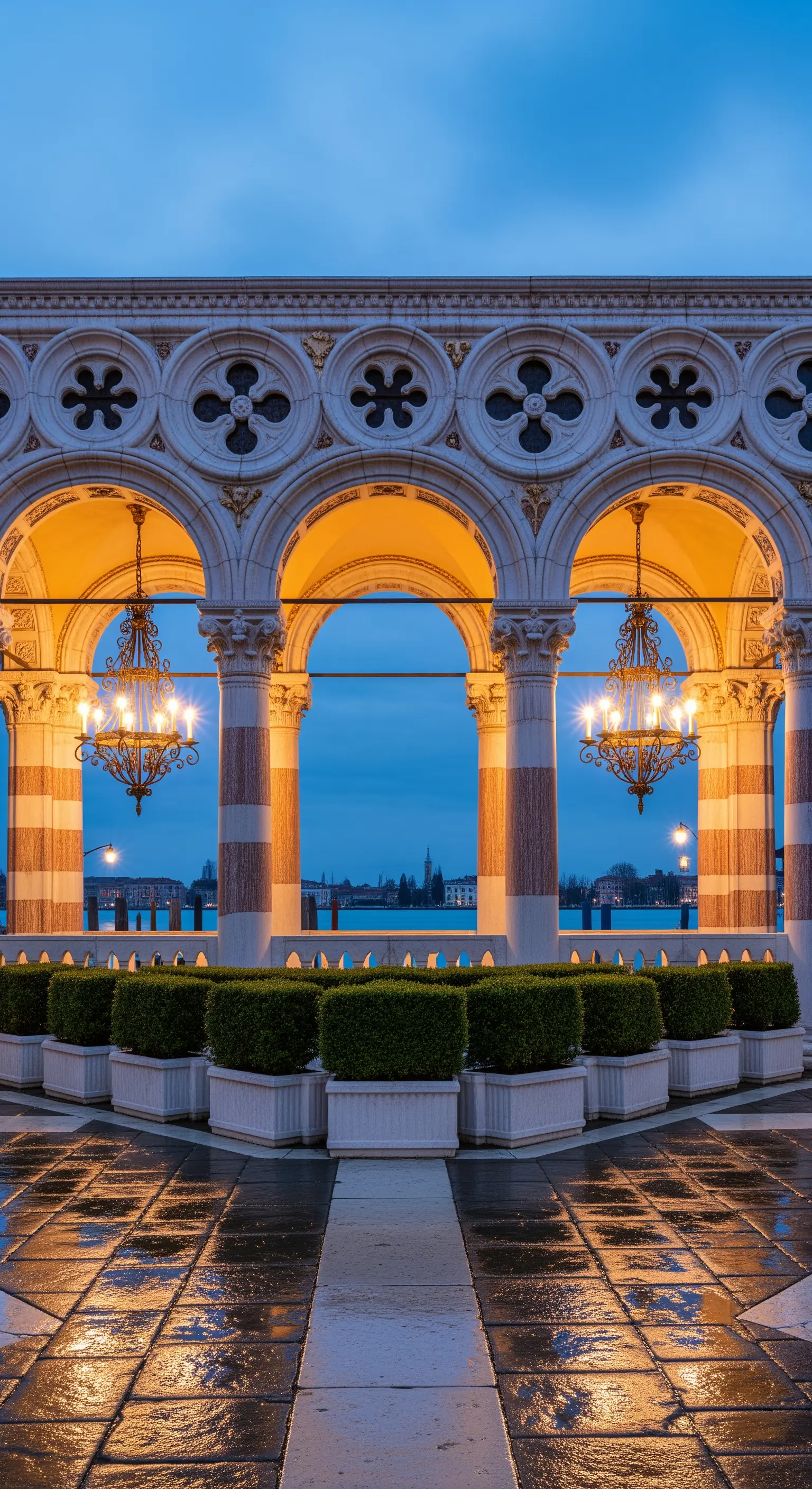 Loggia in stile gotico veneziano con archi, colonne bicolori e lampadari classici affacciata sull'acqua