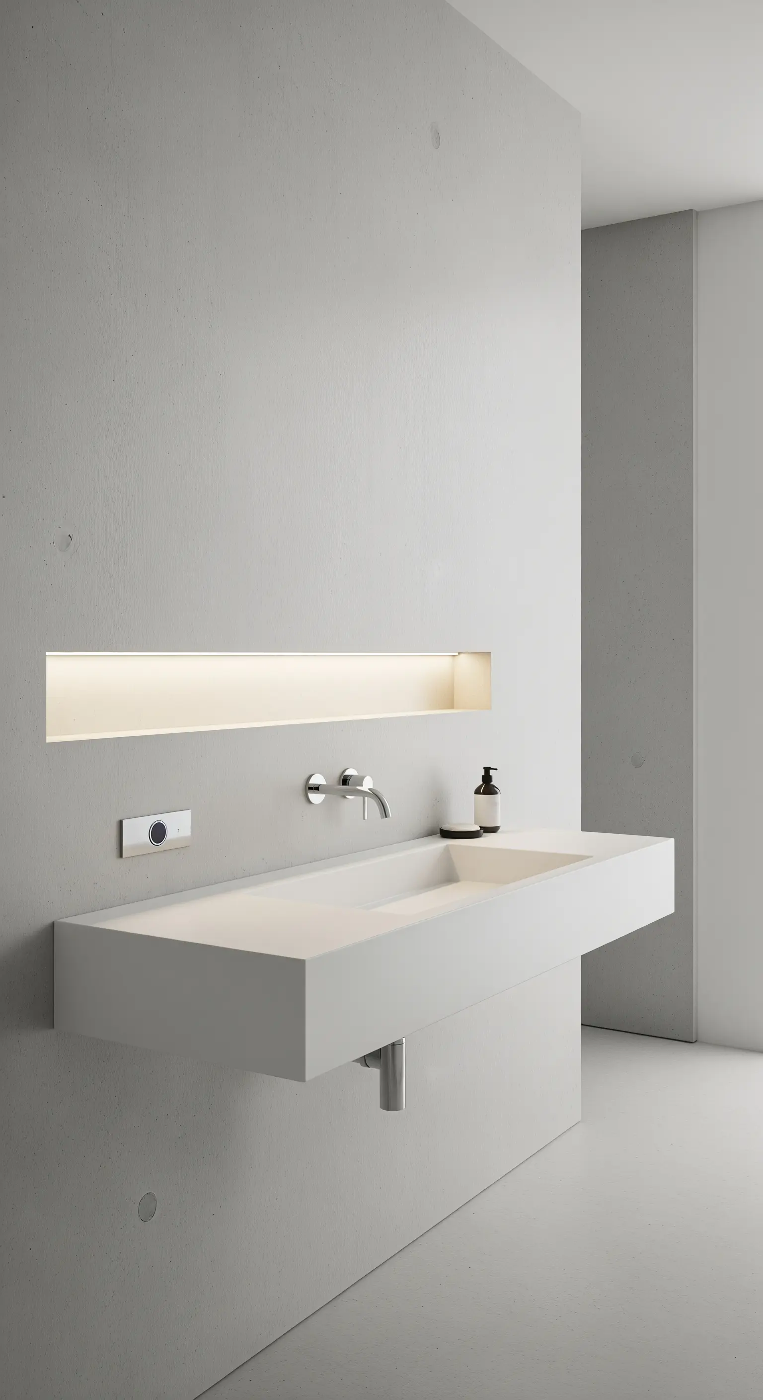 Lavabo bianco sospeso in un bagno minimalista, con una nicchia retroilluminata nella parete.