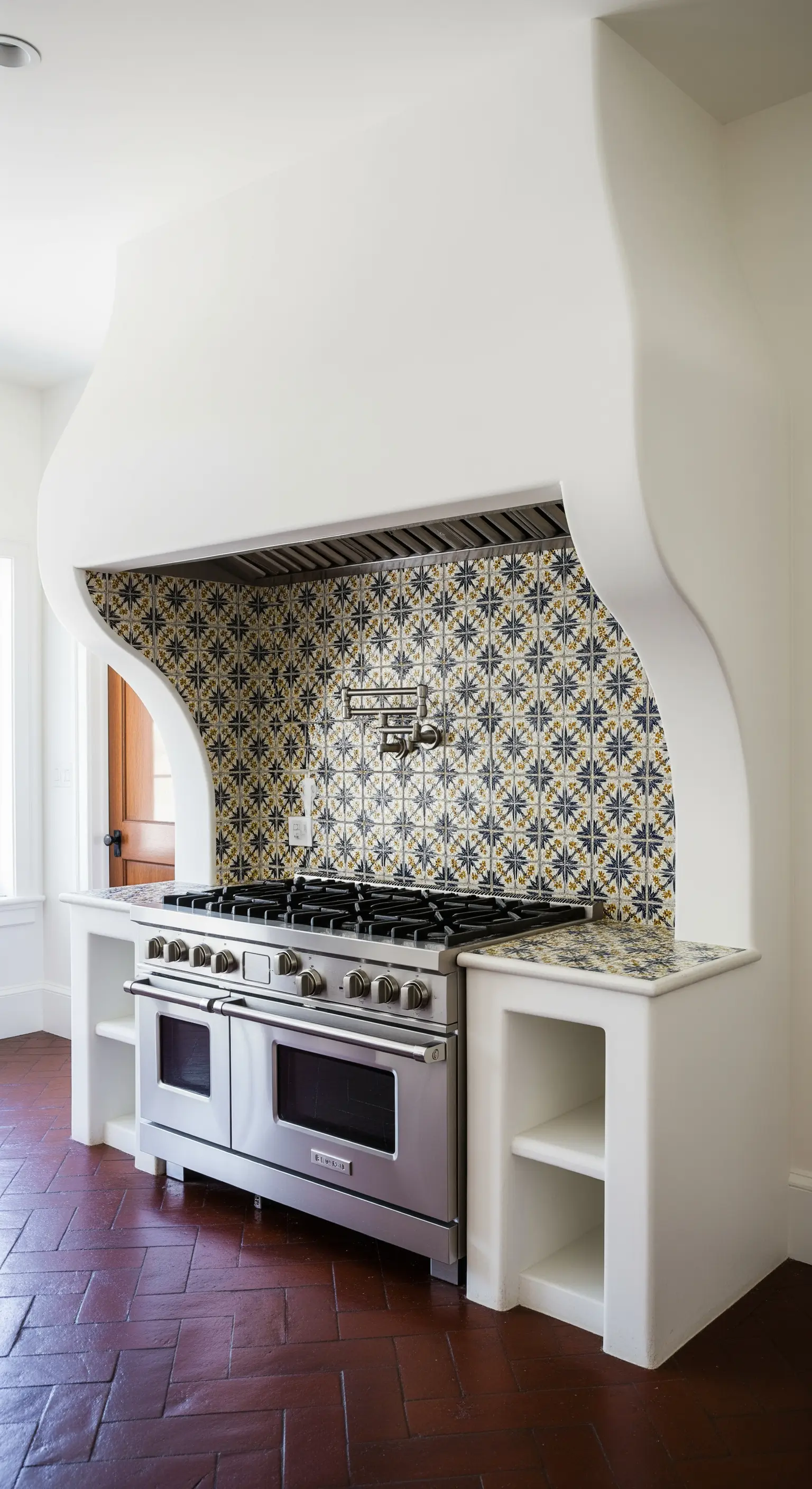 Nicchia per i fornelli con paraschizzi in maioliche blu e oro e struttura in muratura bianca.