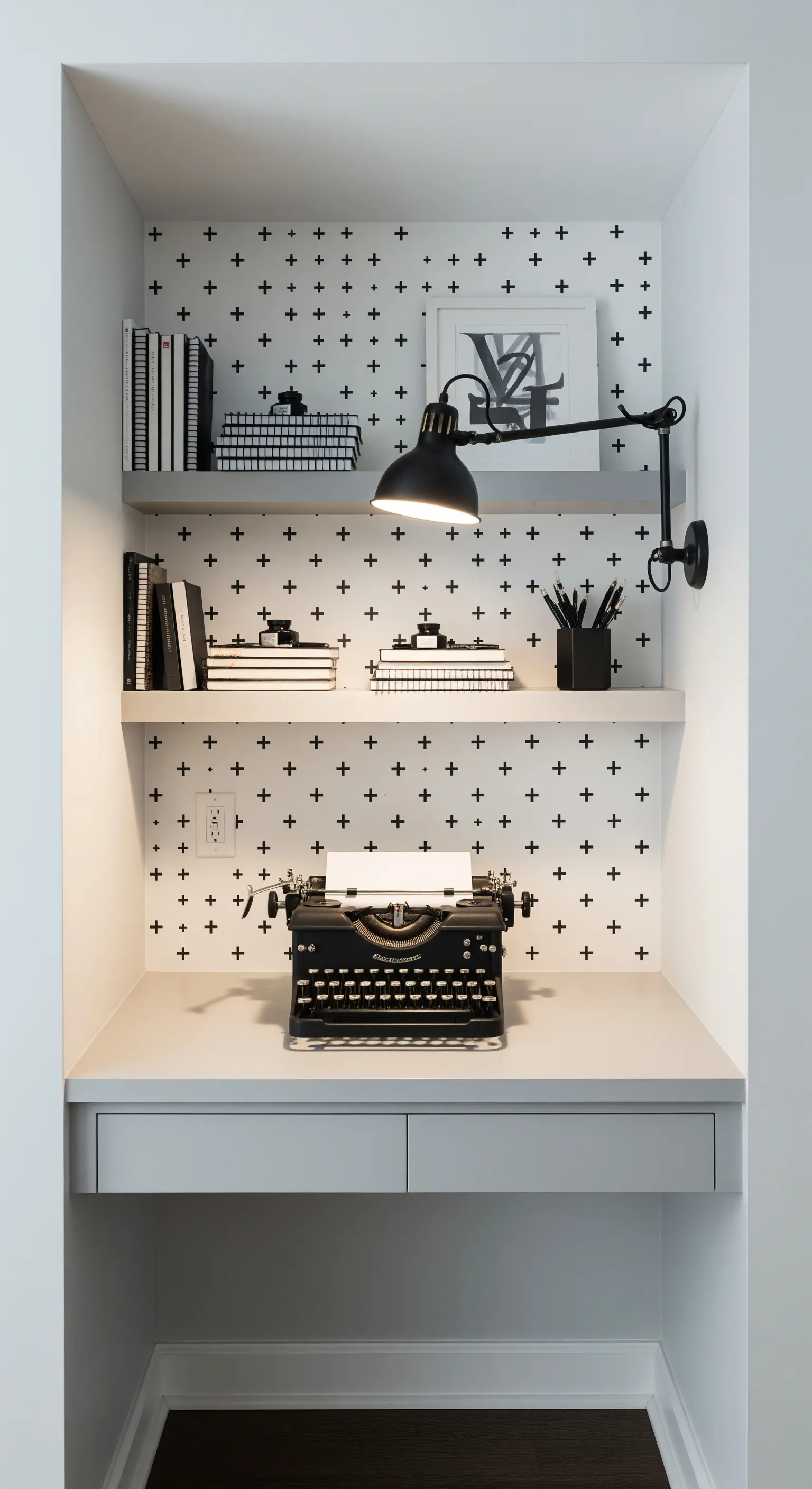 Piccolo studio in una nicchia con carta da parati a croci e mensole bianche.