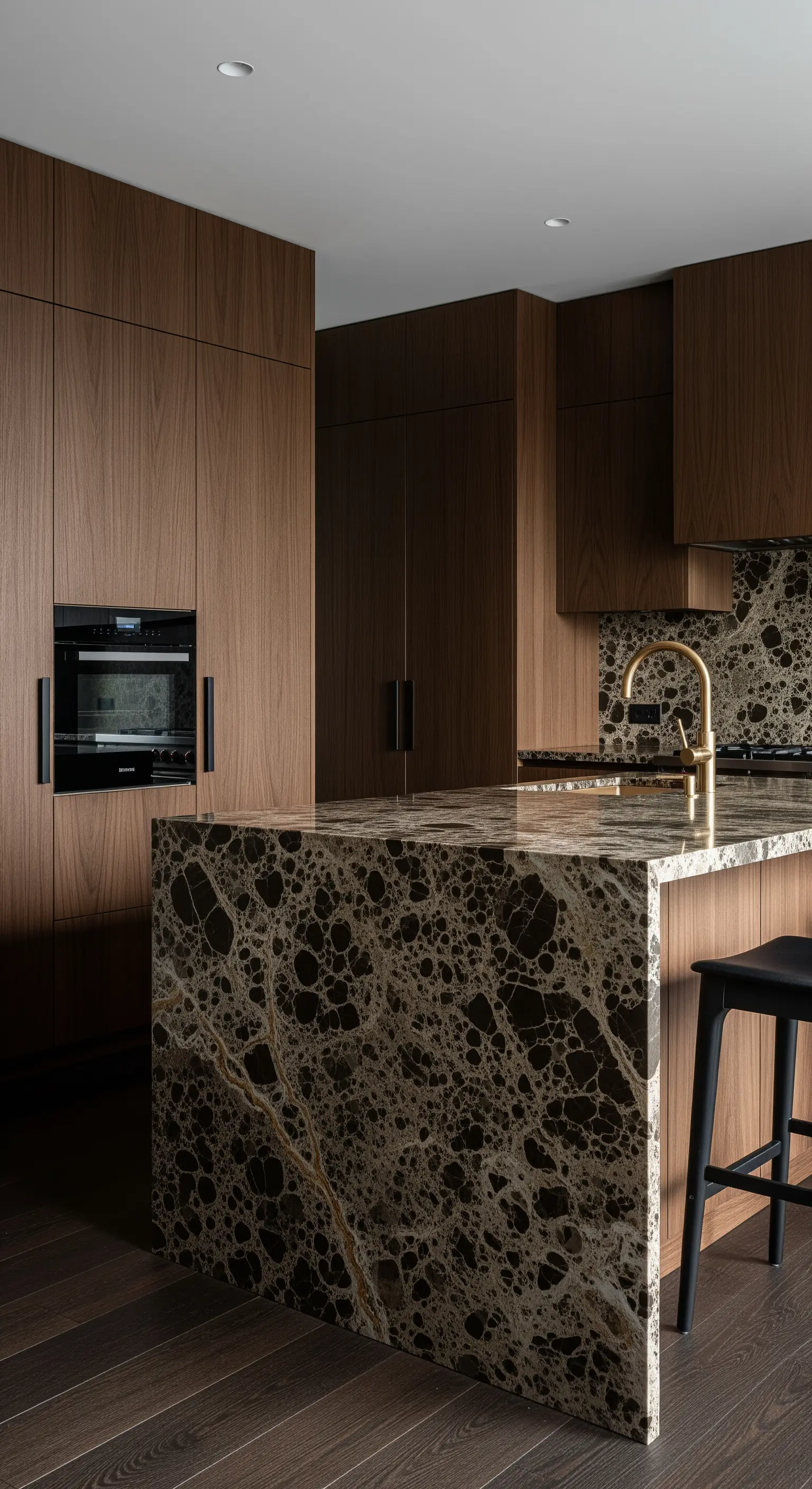 Isola in marmo scuro con venature dorate in una cucina moderna con mobili in legno di noce.