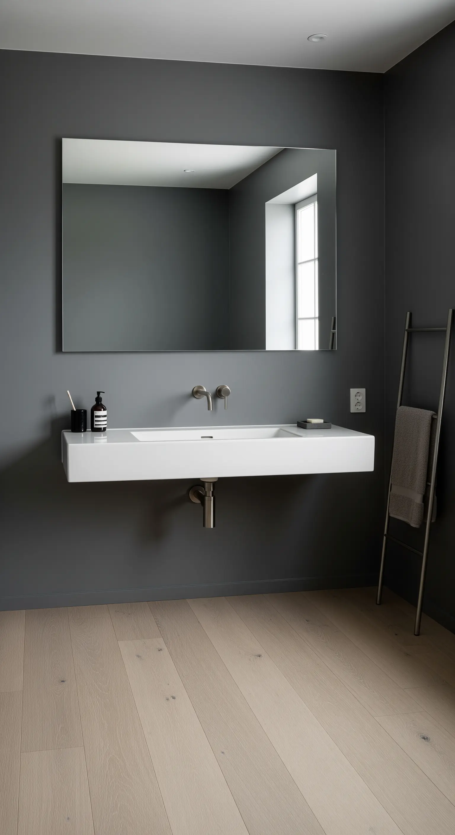 Bagno minimalista con pareti grigie, lavabo bianco sospeso e pavimento in legno.