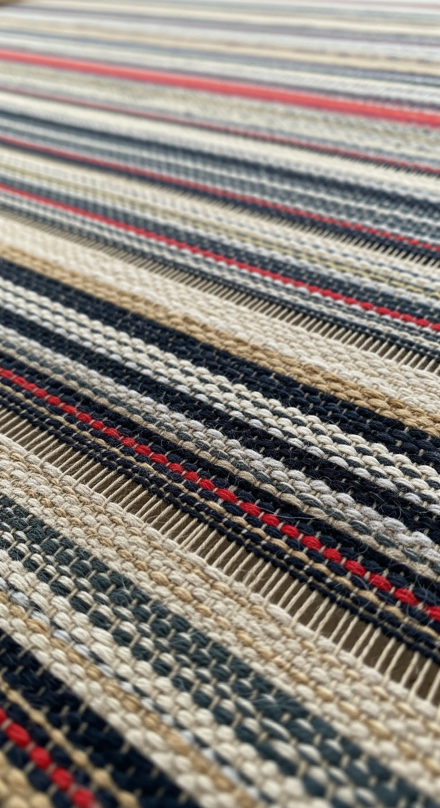 Dettaglio di un tessuto resistente a trama fitta con righe in colori naturali.