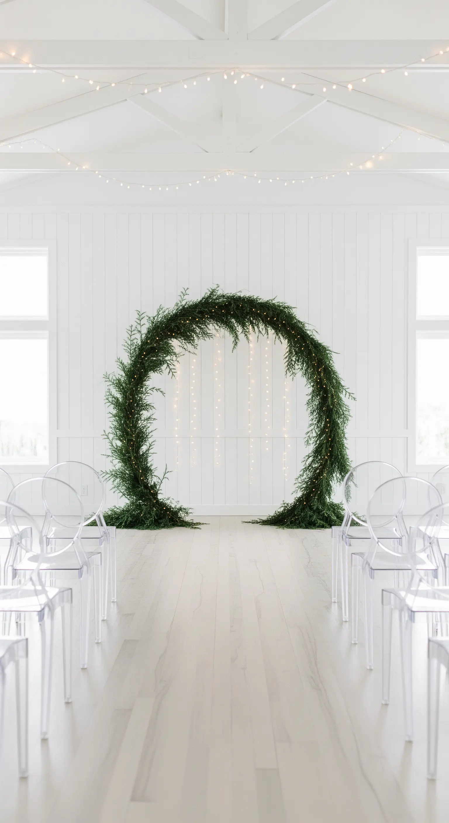 Cerimonia minimalista con un arco circolare di pino e lucine a cascata.