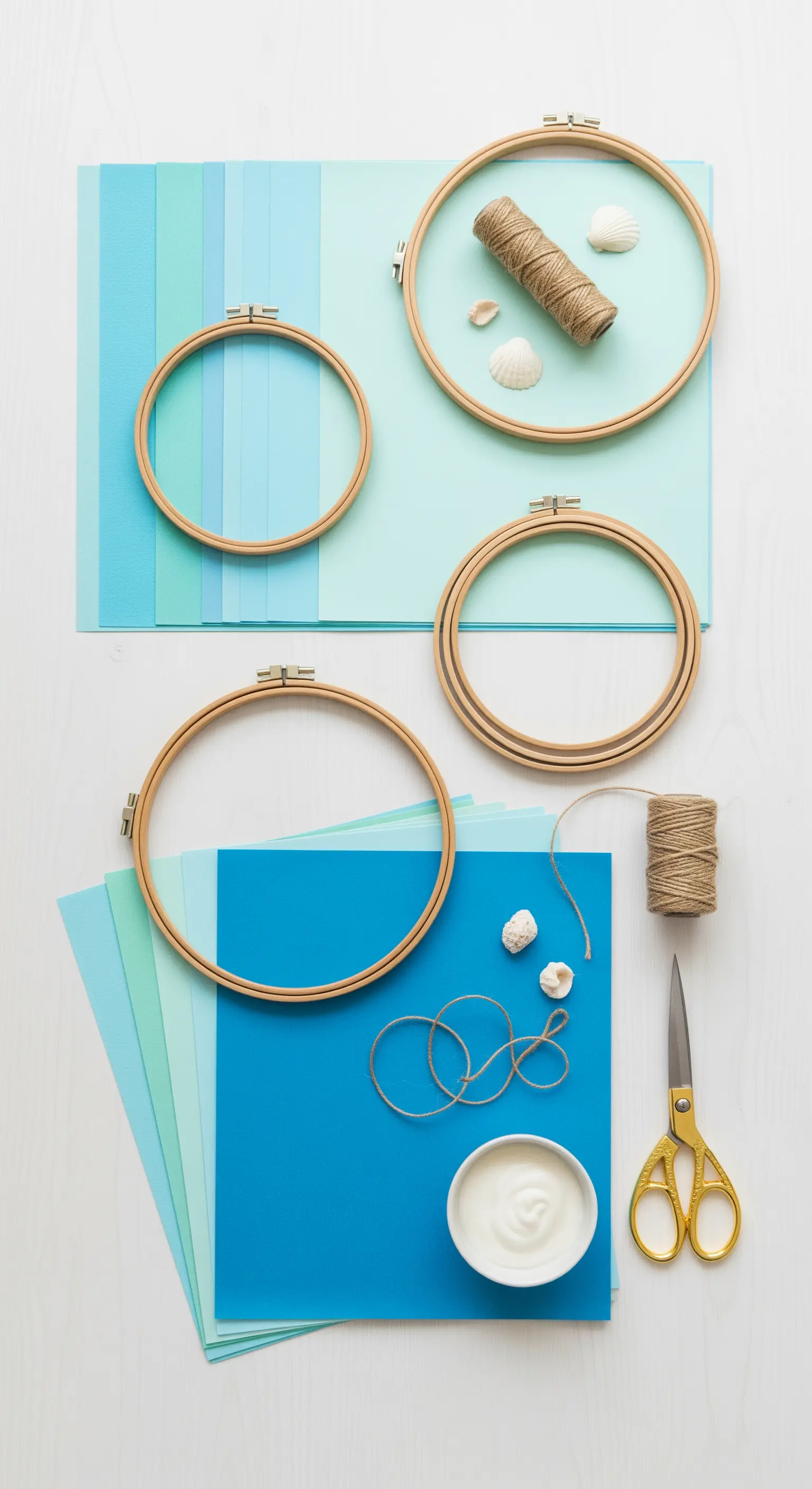 Materiali per un progetto DIY: telai da ricamo in legno, fogli di carta colorata, spago e colla.