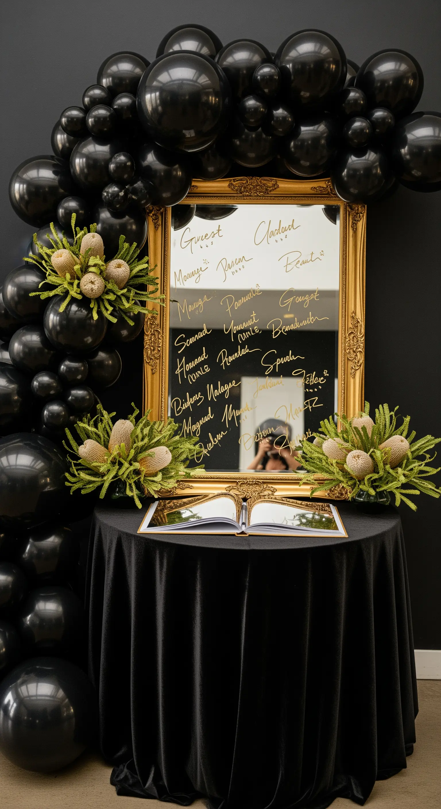Specchio dorato usato come guest book, incorniciato da un arco di palloncini neri.