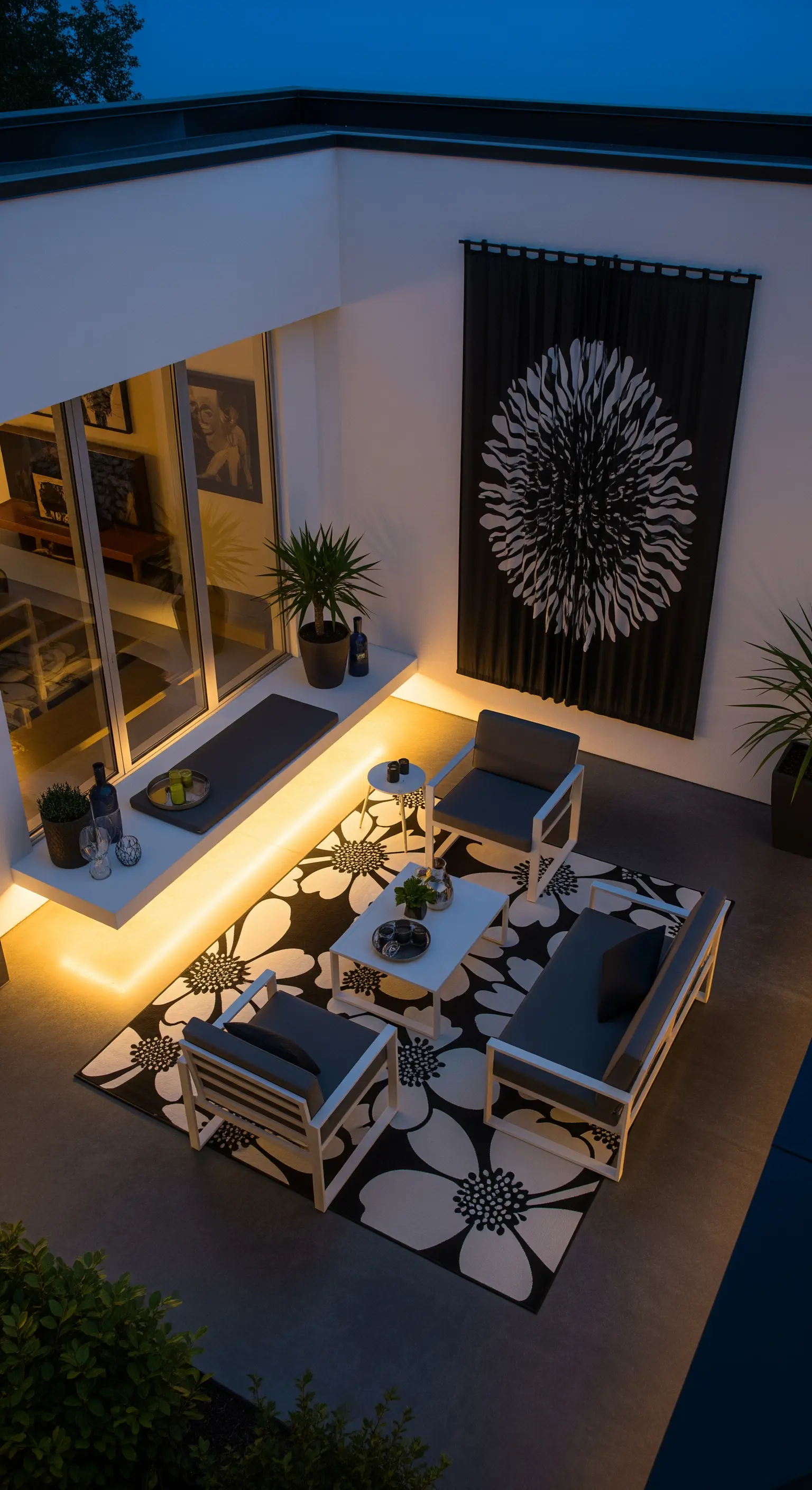 Patio moderno con illuminazione LED sotto la panca, arredi bianchi e tappeto floreale B/N.
