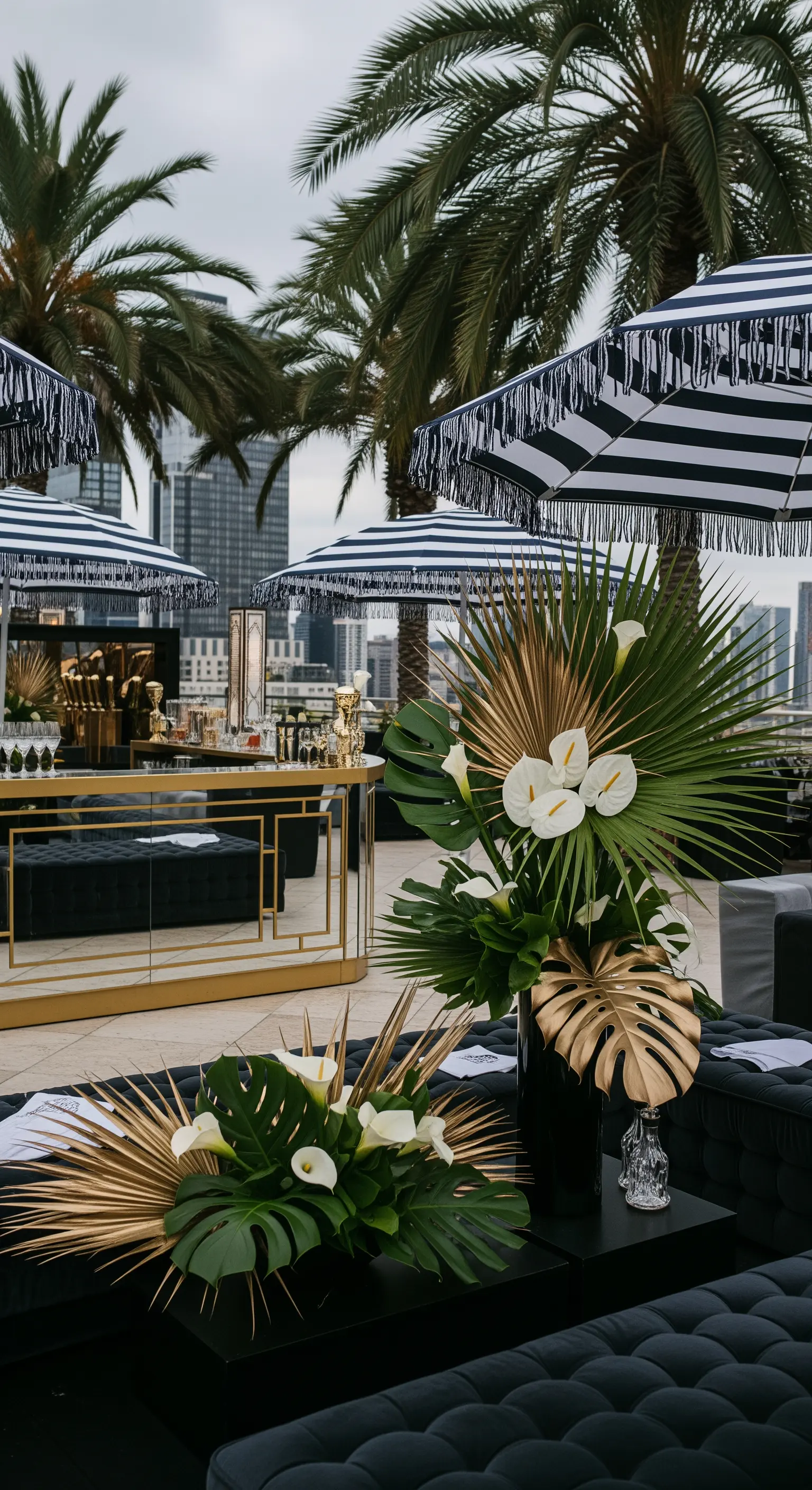 Allestimento nero e oro con ombrelloni a righe e foglie di palma dorate come decorazione