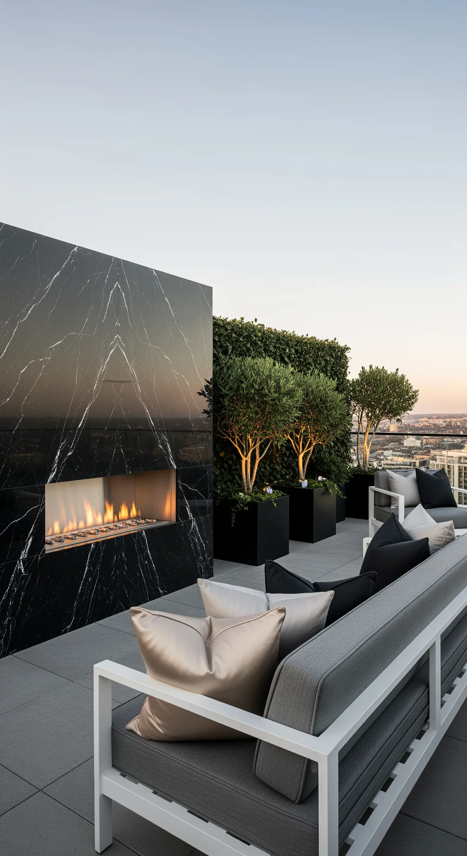 Terrazza di lusso con un imponente camino in marmo nero, divani bianchi e una parete verde.