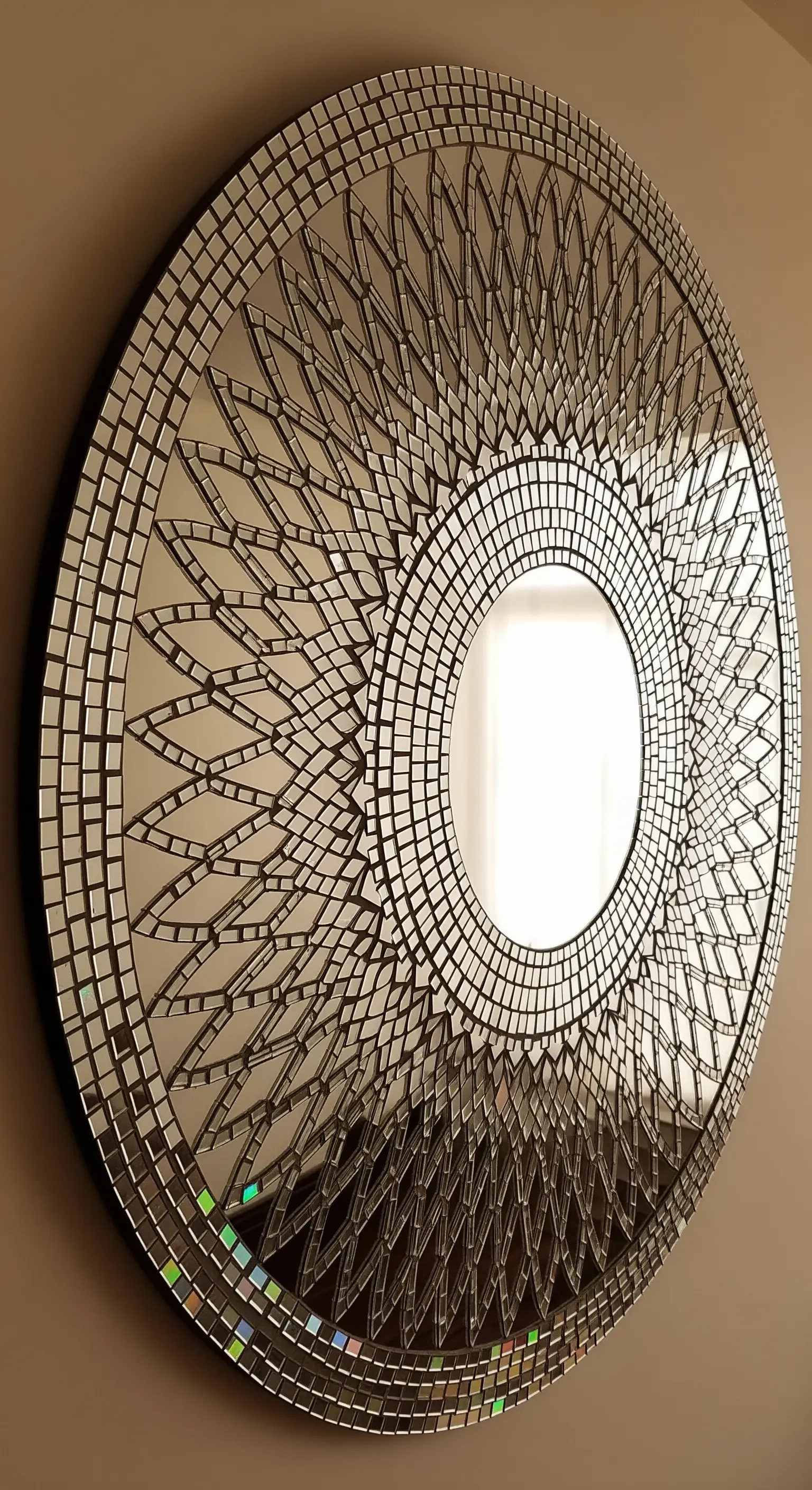 Grande specchio rotondo con una complessa cornice a mosaico che crea un motivo a mandala.
