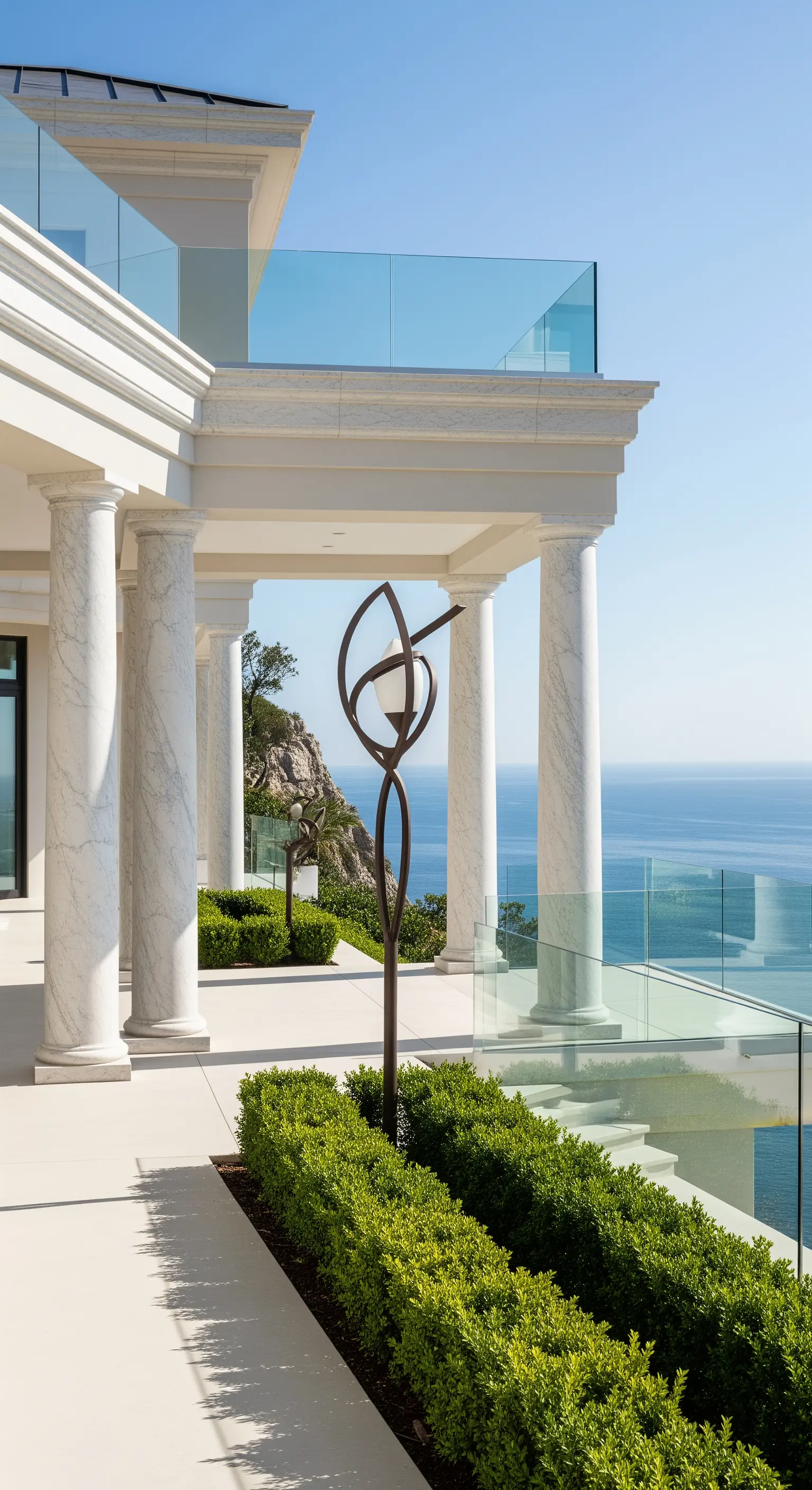 Portico in marmo bianco con colonne classiche e moderni parapetti in vetro vista mare.
