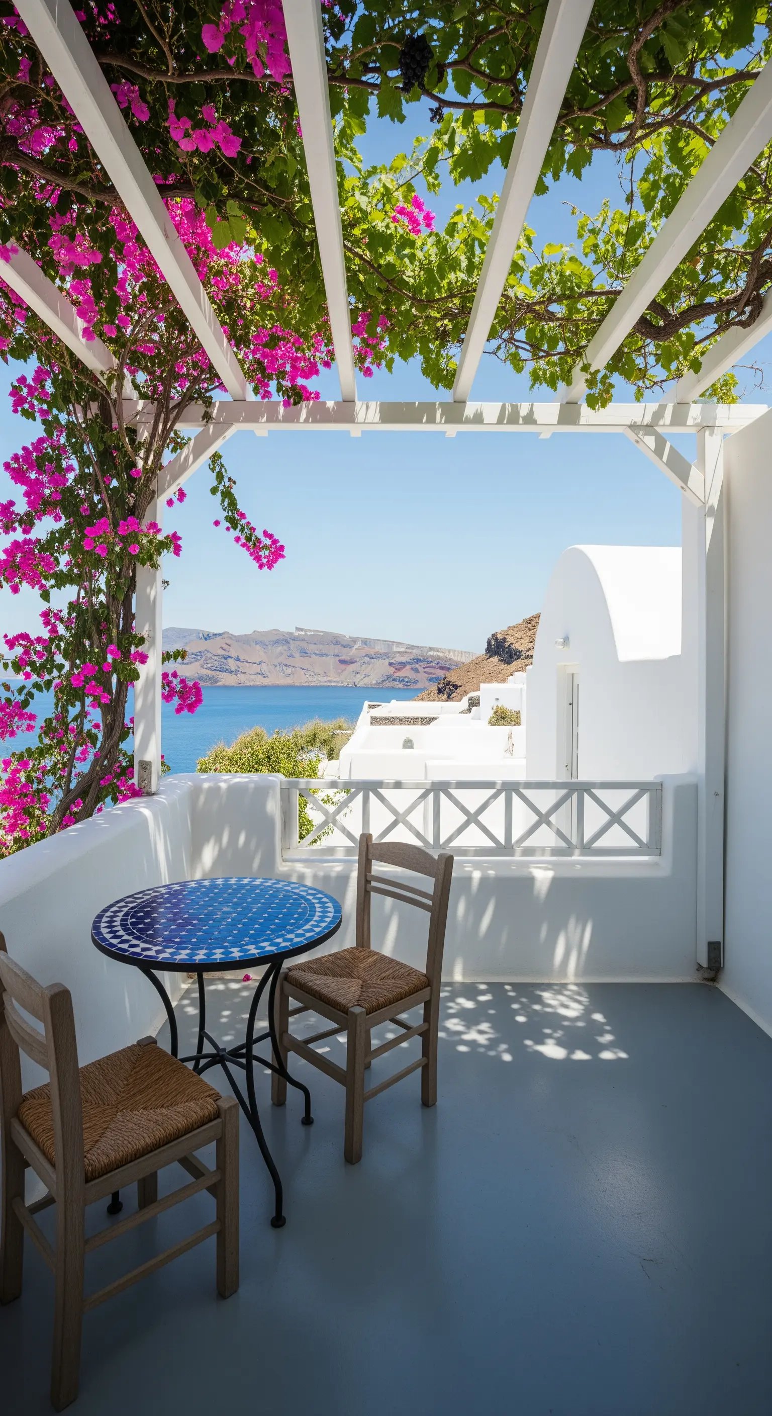 Balcone bianco a Santorini con pergolato, bouganville e tavolino in mosaico blu
