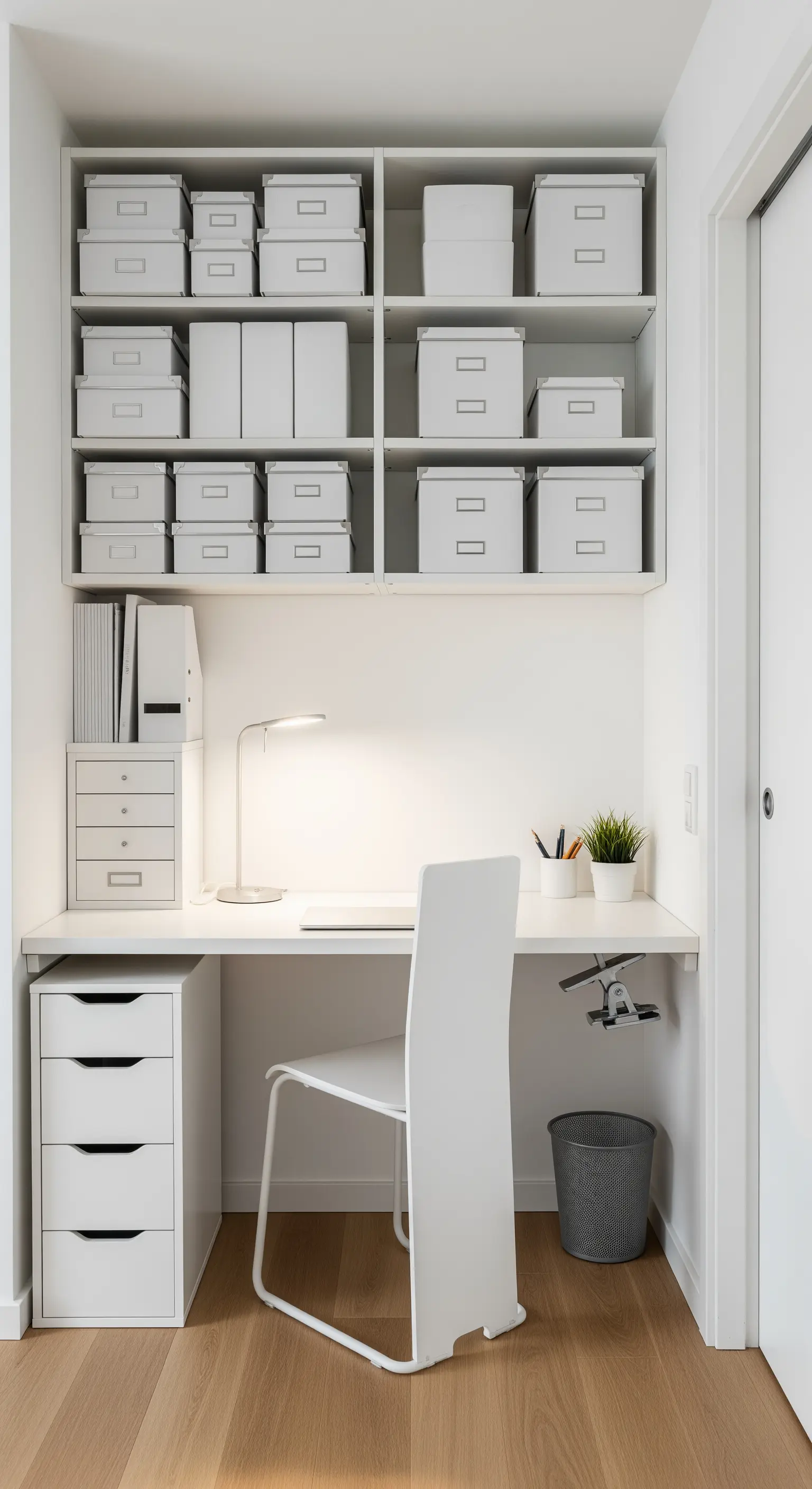 Piccolo home office bianco in una nicchia, con scaffali pieni di scatole coordinate e una cassettiera.