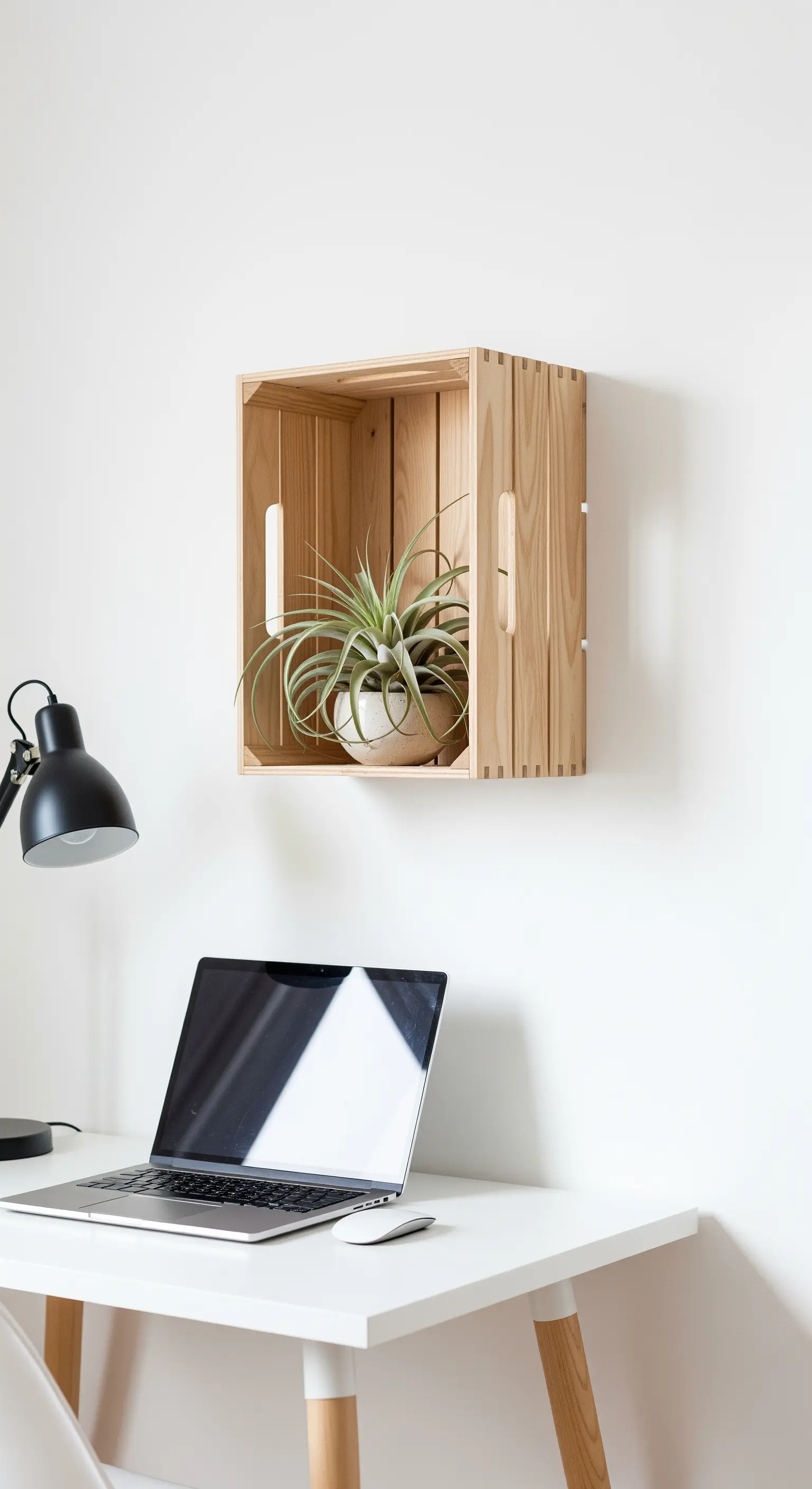 Singola cassetta di legno naturale usata come mensola sopra una scrivania bianca minimalista.