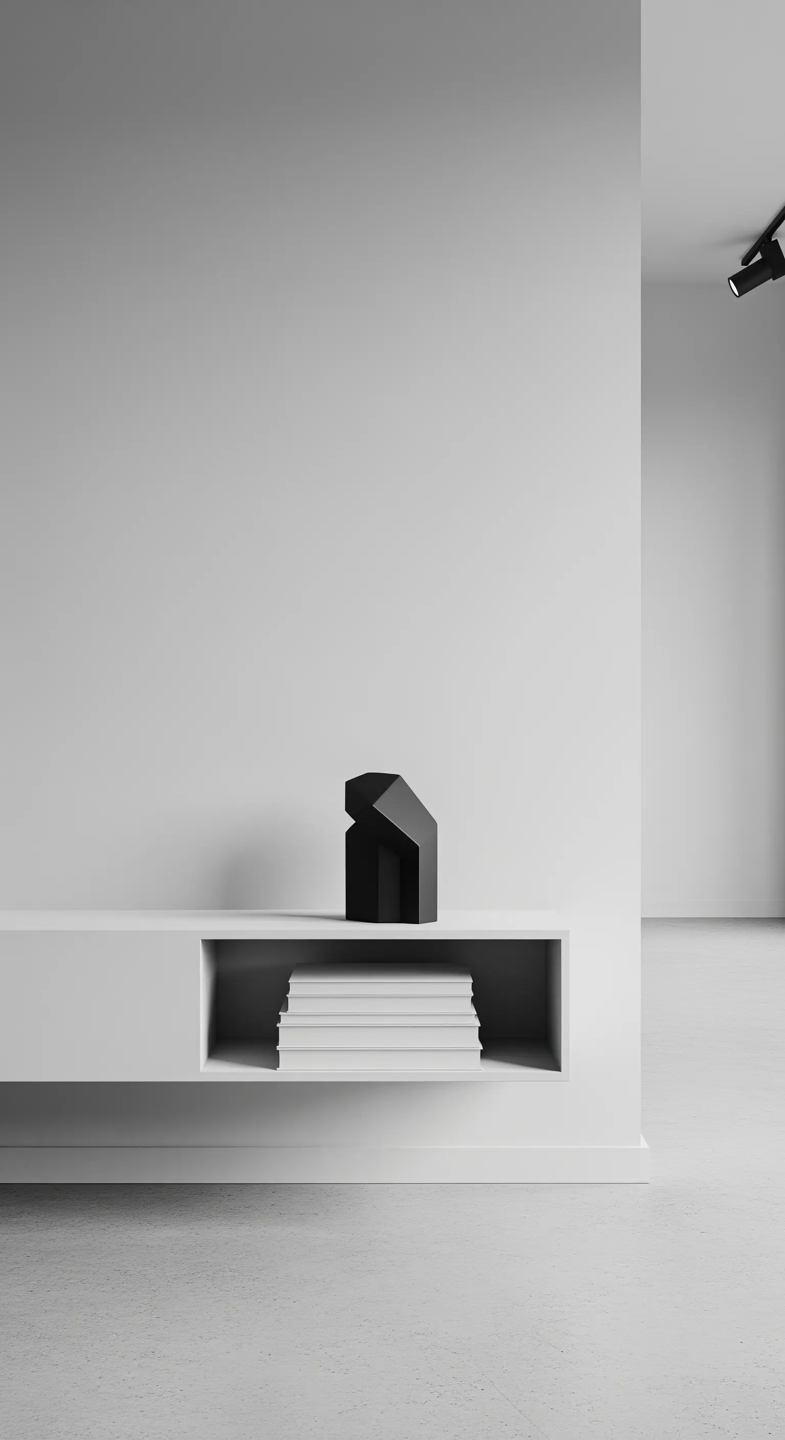 Pila di libri con copertina bianca in una nicchia di un mobile minimalista, accanto a una scultura nera.