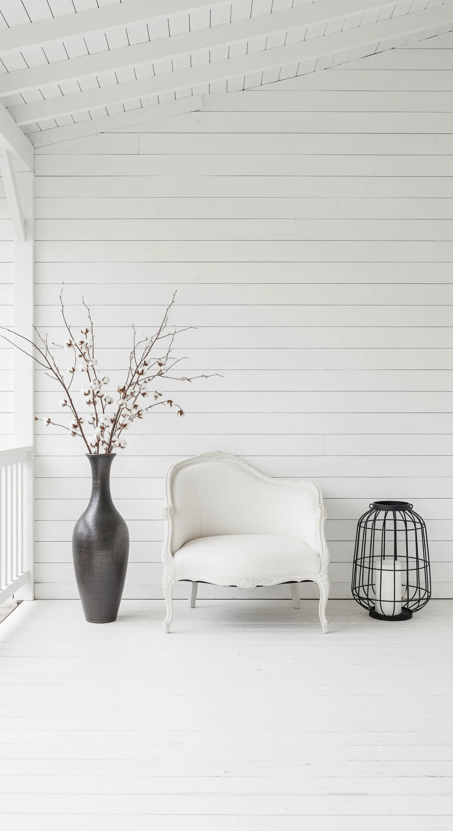 Veranda minimalista total white con poltroncina antica, vaso scuro e lanterna nera.