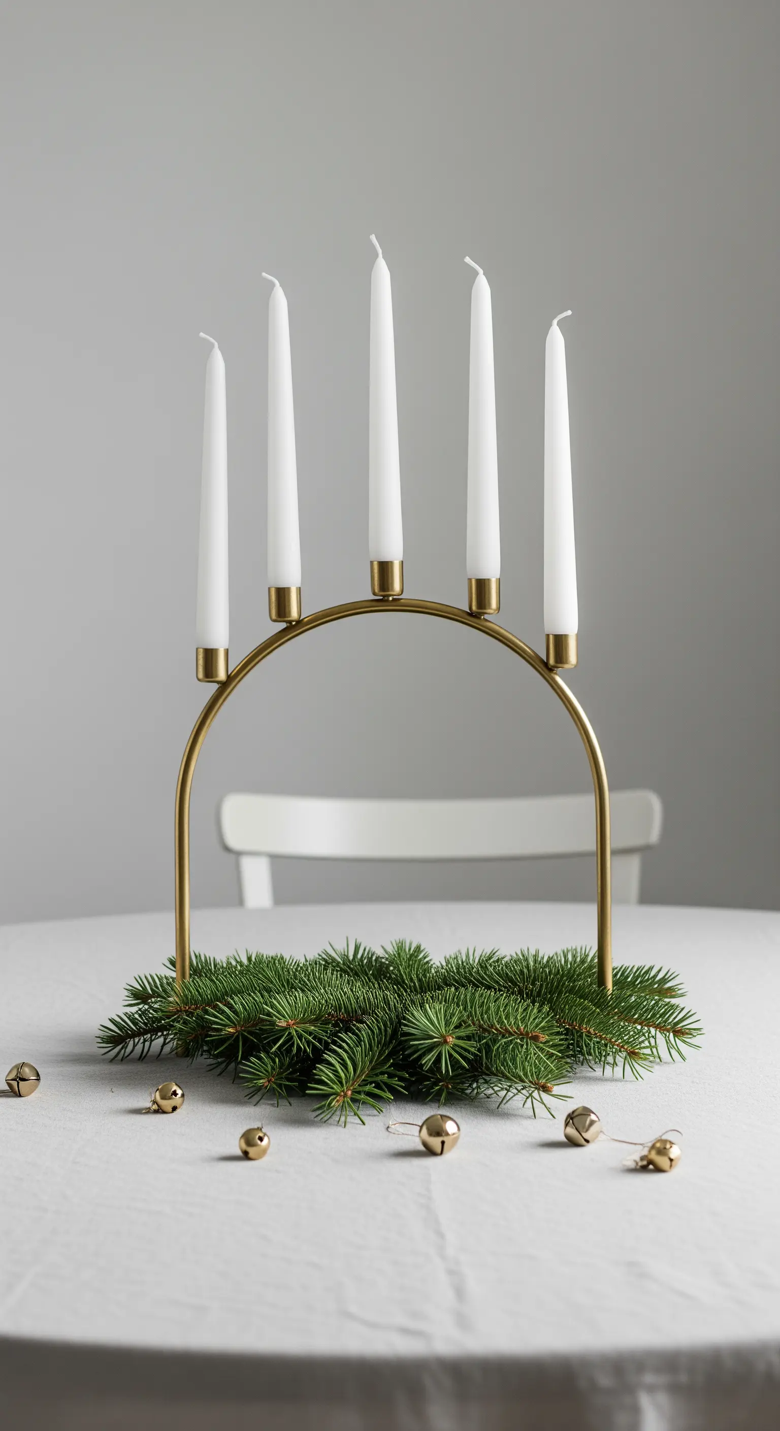 Centrotavola minimalista scandinavo con candelabro ad arco dorato e rami di pino.