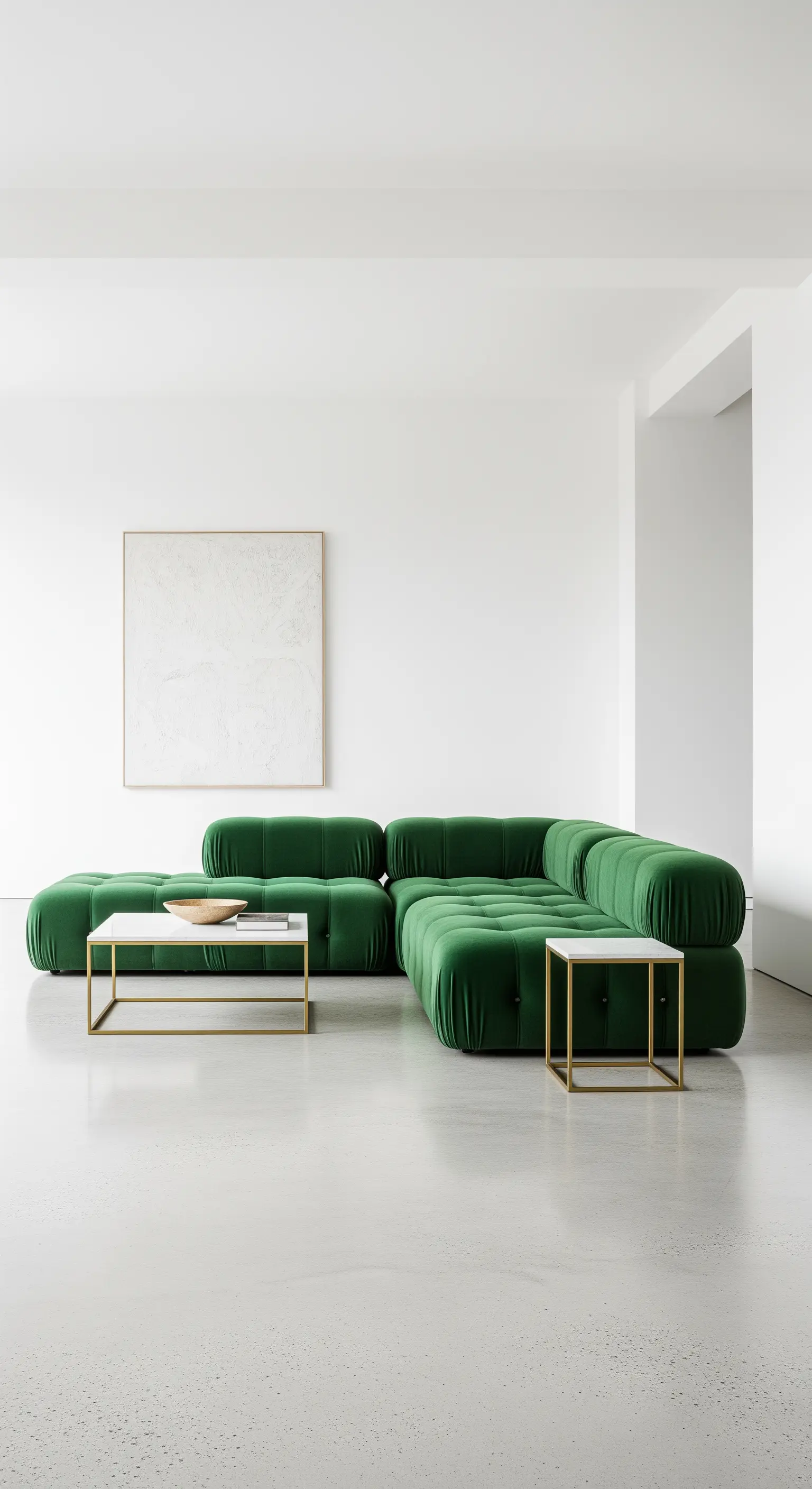 Divano modulare verde in un ambiente minimalista bianco con tavolino in ottone e marmo.